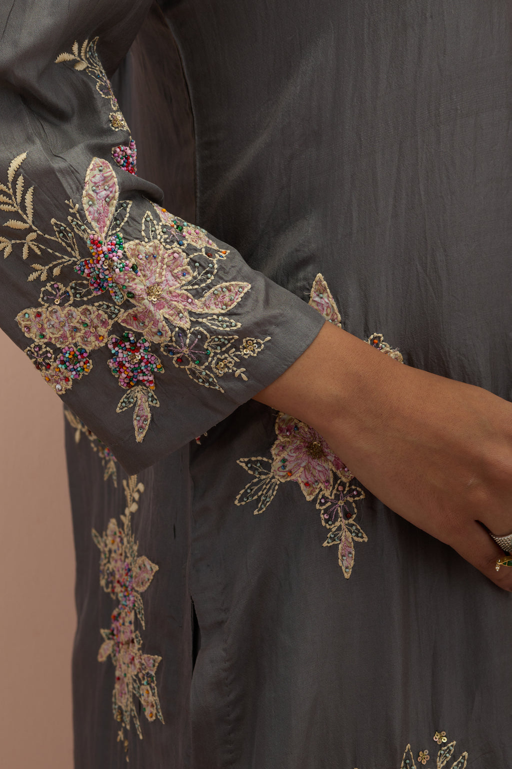 Iron grey silk straight kurta set with randomly placed hand block printed appliquéd flowers, highlighted with sequins and multi-colored beads.