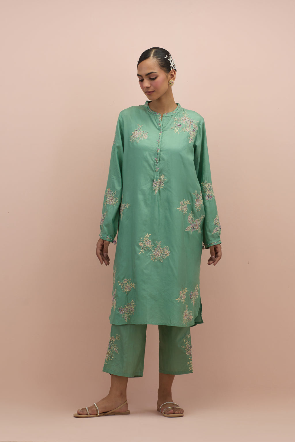 Jade green silk short shirt kurta with all-over hand block printed appliqué, highlighted with sequins and multi colored beads, paired with jade green silk ankle length straight pants with hand block printed appliqué motifs at the sides.