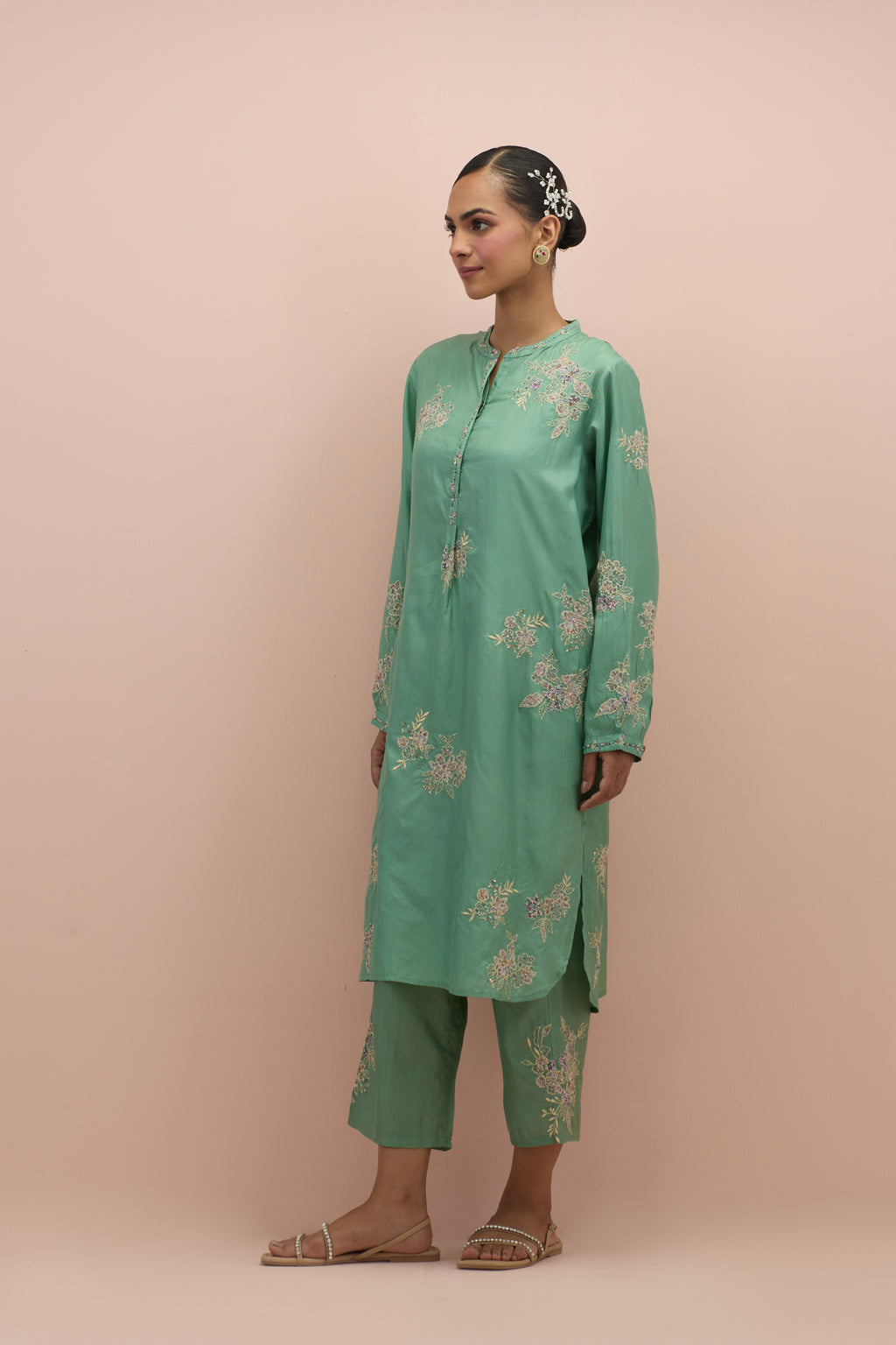 Jade green silk short shirt kurta with all-over hand block printed appliqué, highlighted with sequins and multi colored beads, paired with jade green silk ankle length straight pants with hand block printed appliqué motifs at the sides.