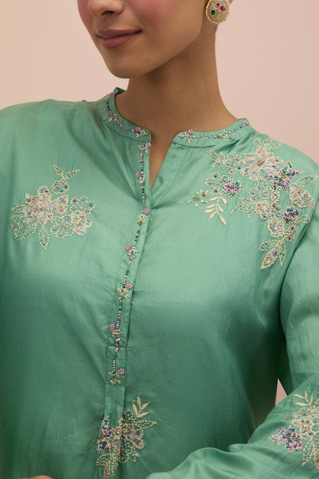 Jade green silk short shirt kurta with all-over hand block printed appliqué, highlighted with sequins and multi colored beads, paired with jade green silk ankle length straight pants with hand block printed appliqué motifs at the sides.