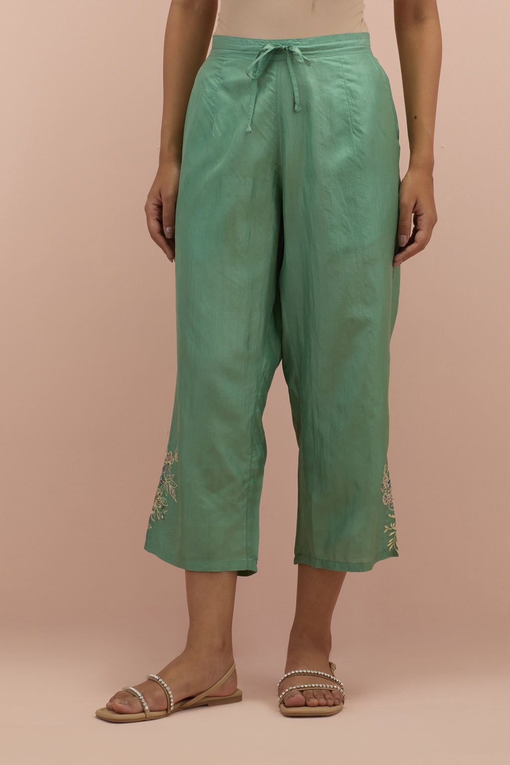 Jade green silk ankle length straight pants with hand block printed appliqué motifs at the sides, highlighted with sequins and multi-colored beads.