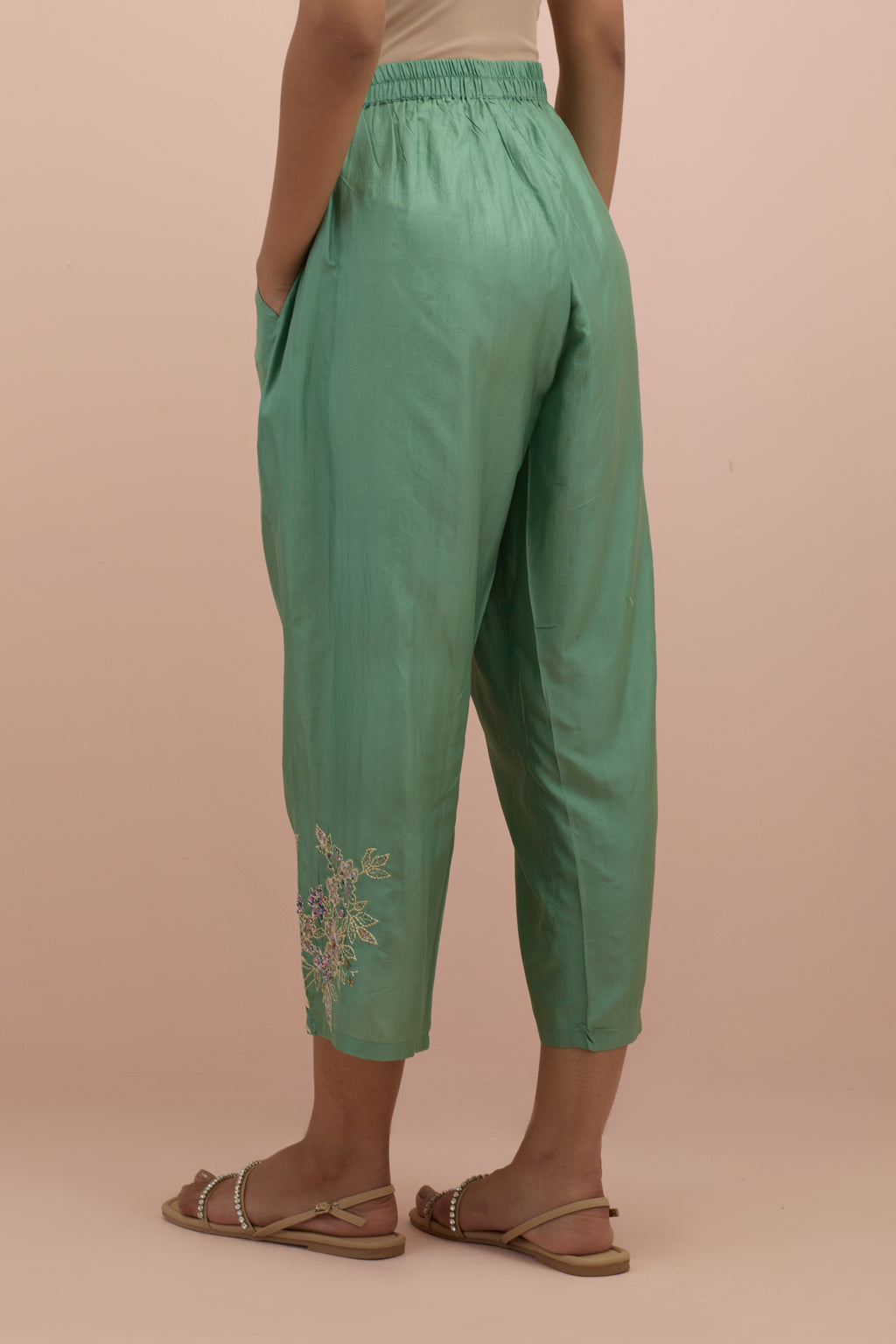 Jade green silk ankle length straight pants with hand block printed appliqué motifs at the sides, highlighted with sequins and multi-colored beads.