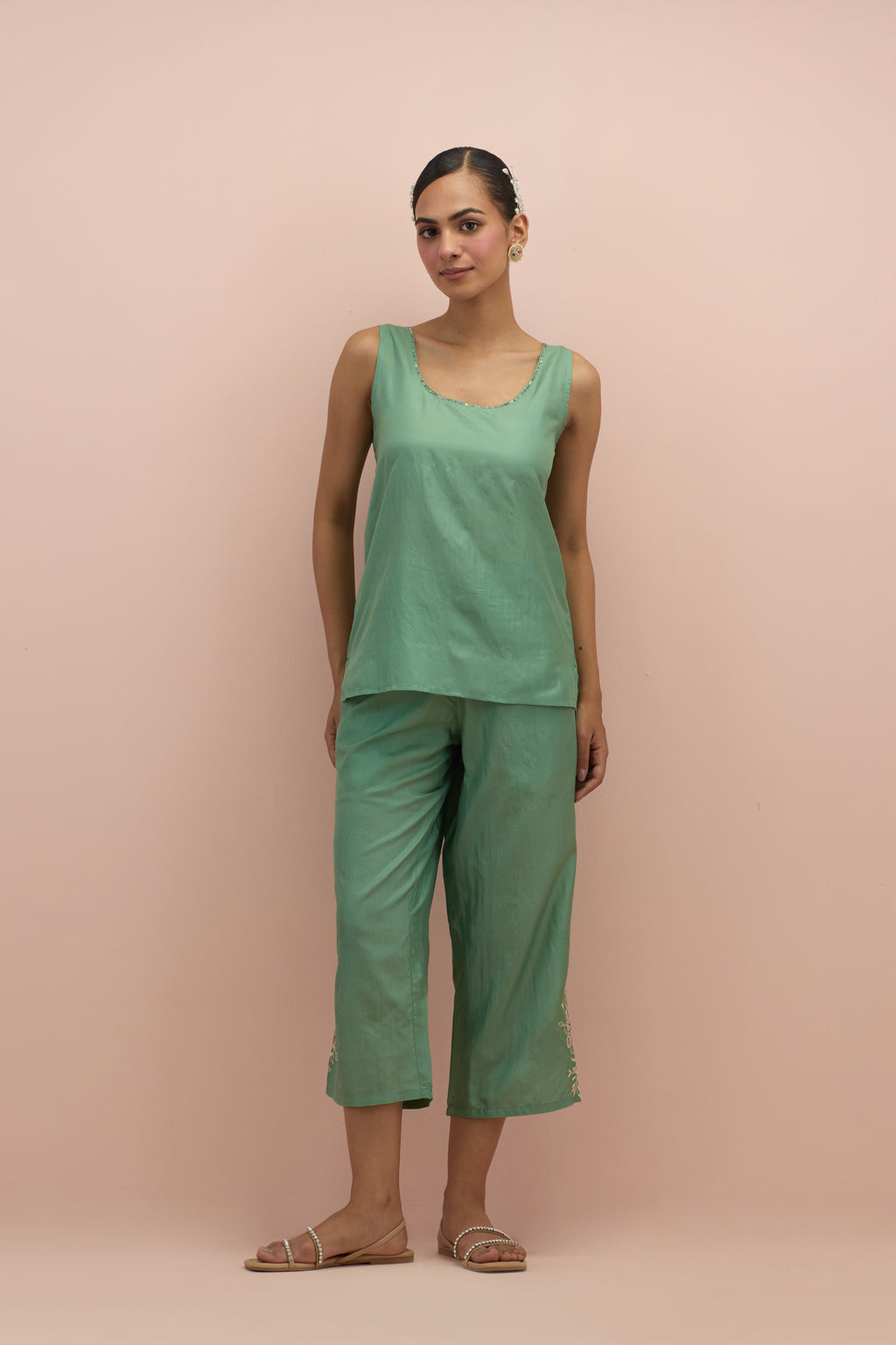 Jade green silk short top with hand block printed appliqué motifs and delicate embroidered flowers, highlighted with sequins and multi-colored beads, paired with jade green silk ankle length straight pants.