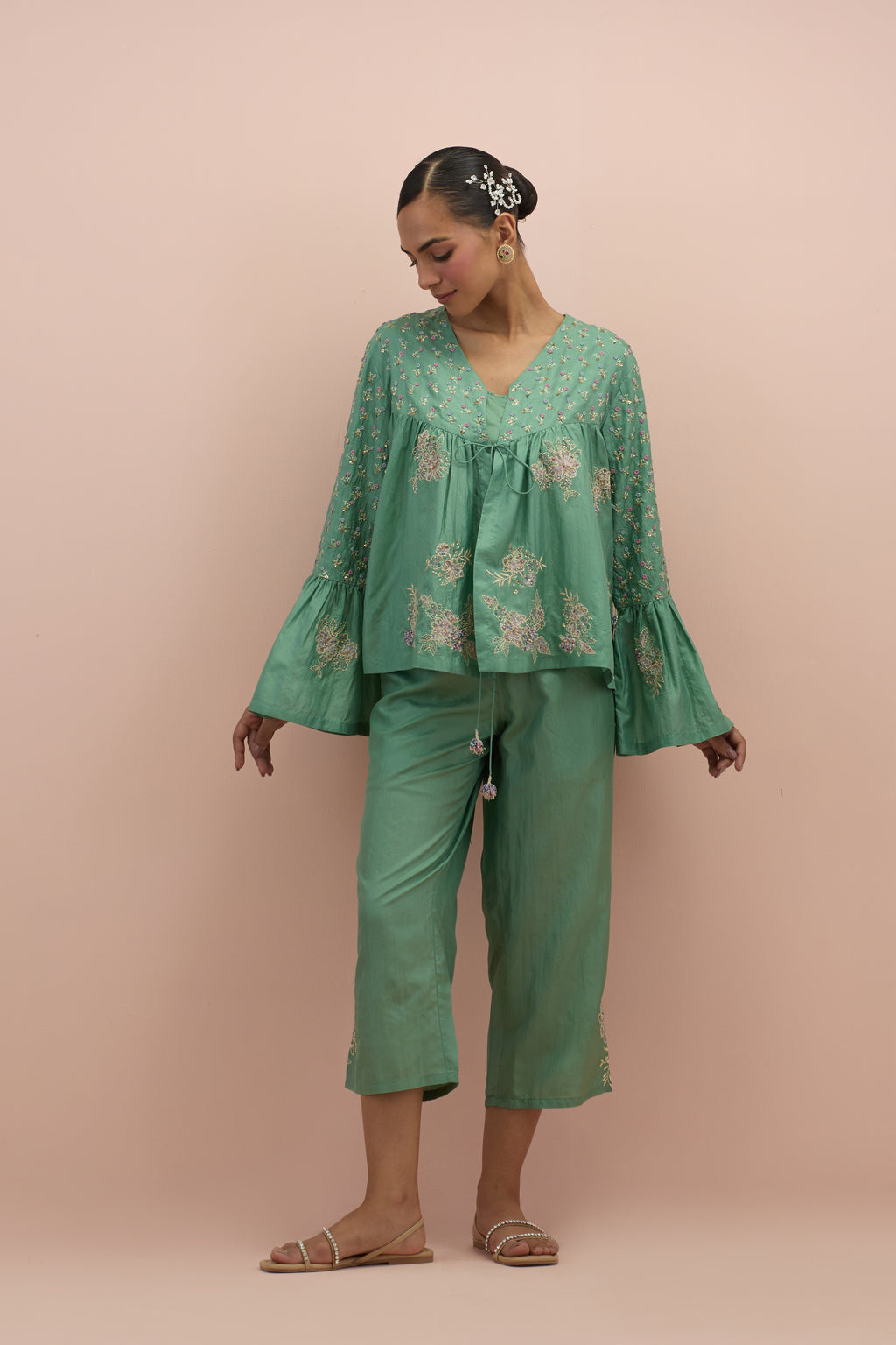 Jade green silk short top with hand block printed appliqué motifs and delicate embroidered flowers, highlighted with sequins and multi-colored beads, paired with jade green silk ankle length straight pants.