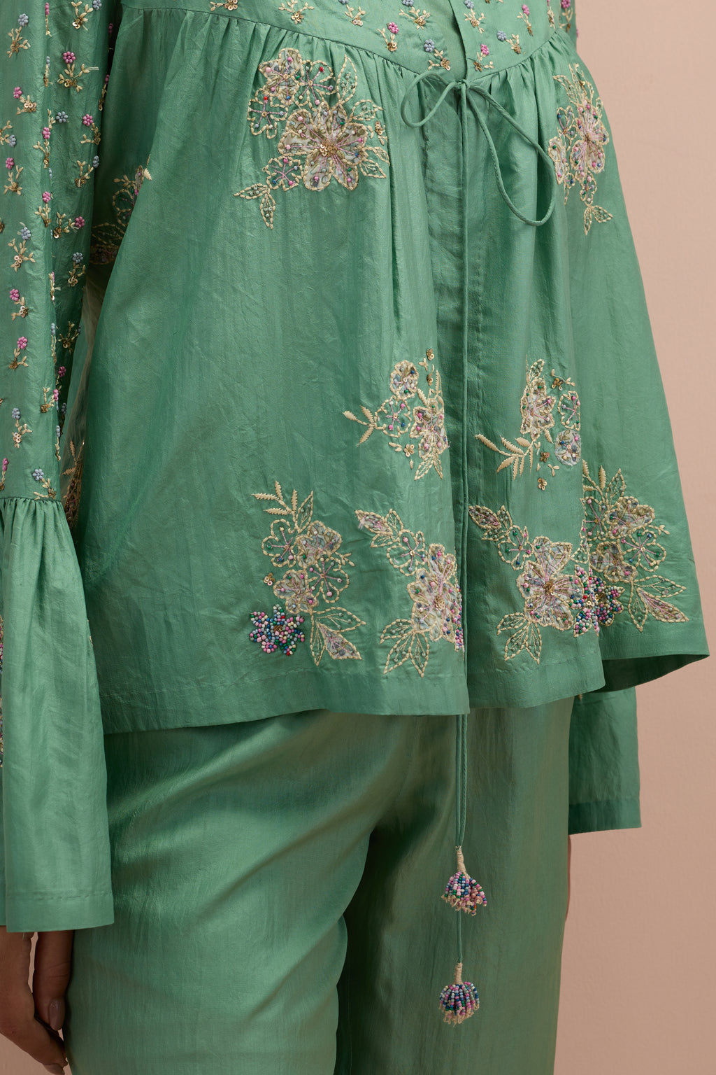 Jade green silk short top with hand block printed appliqué motifs and delicate embroidered flowers, highlighted with sequins and multi-colored beads, paired with jade green silk ankle length straight pants.