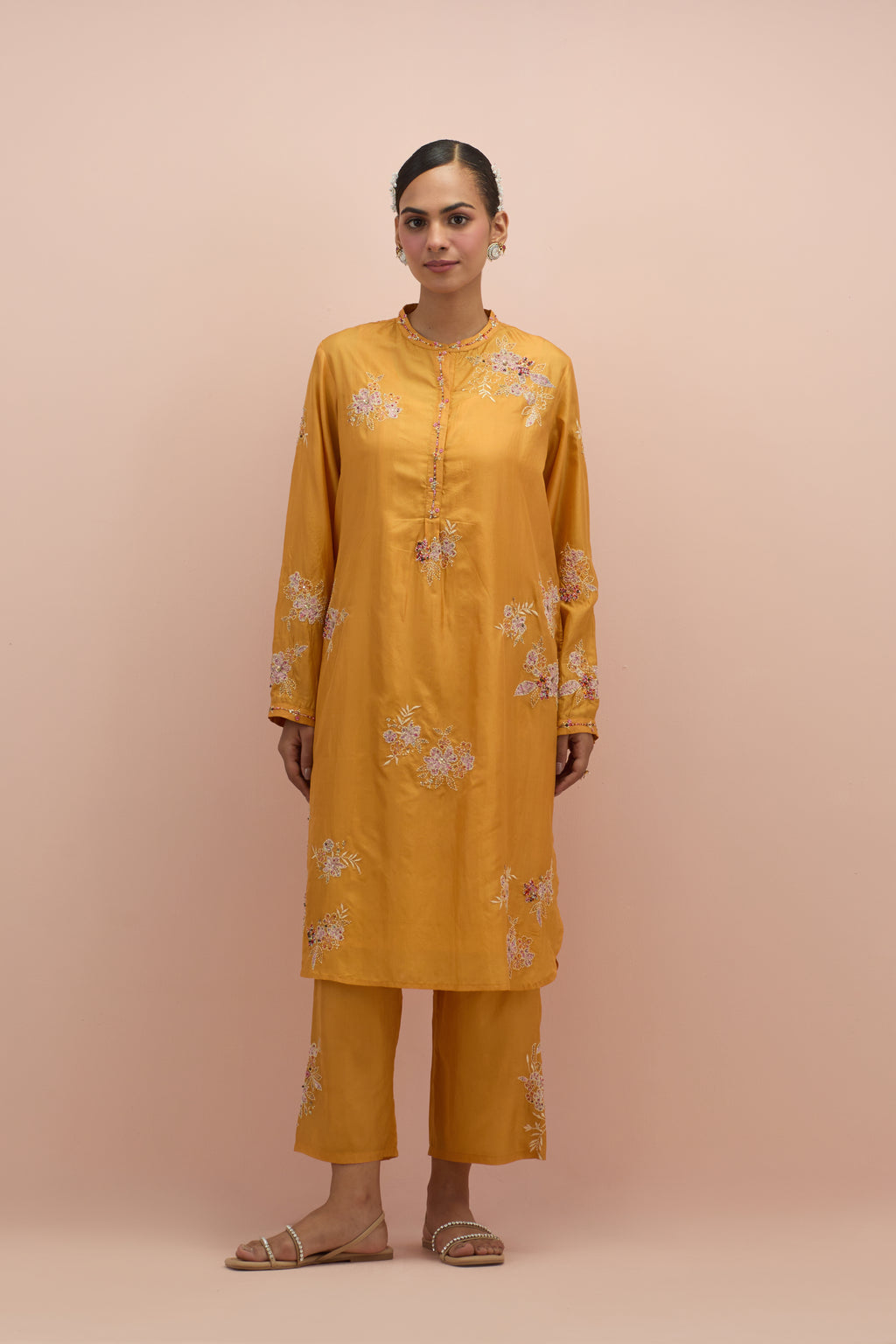 Amber silk short shirt kurta with all-over hand block printed appliqué, highlighted with sequins and multi colored beads, paired with amber silk ankle length straight pants with hand block printed appliqué motifs at the sides.