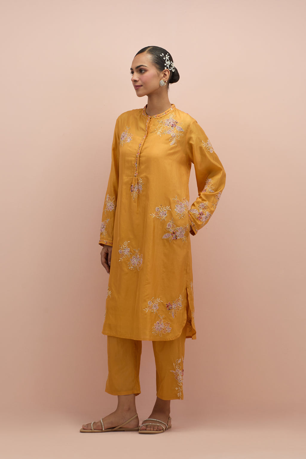 Amber silk short shirt kurta with all-over hand block printed appliqué, highlighted with sequins and multi colored beads, paired with amber silk ankle length straight pants with hand block printed appliqué motifs at the sides.