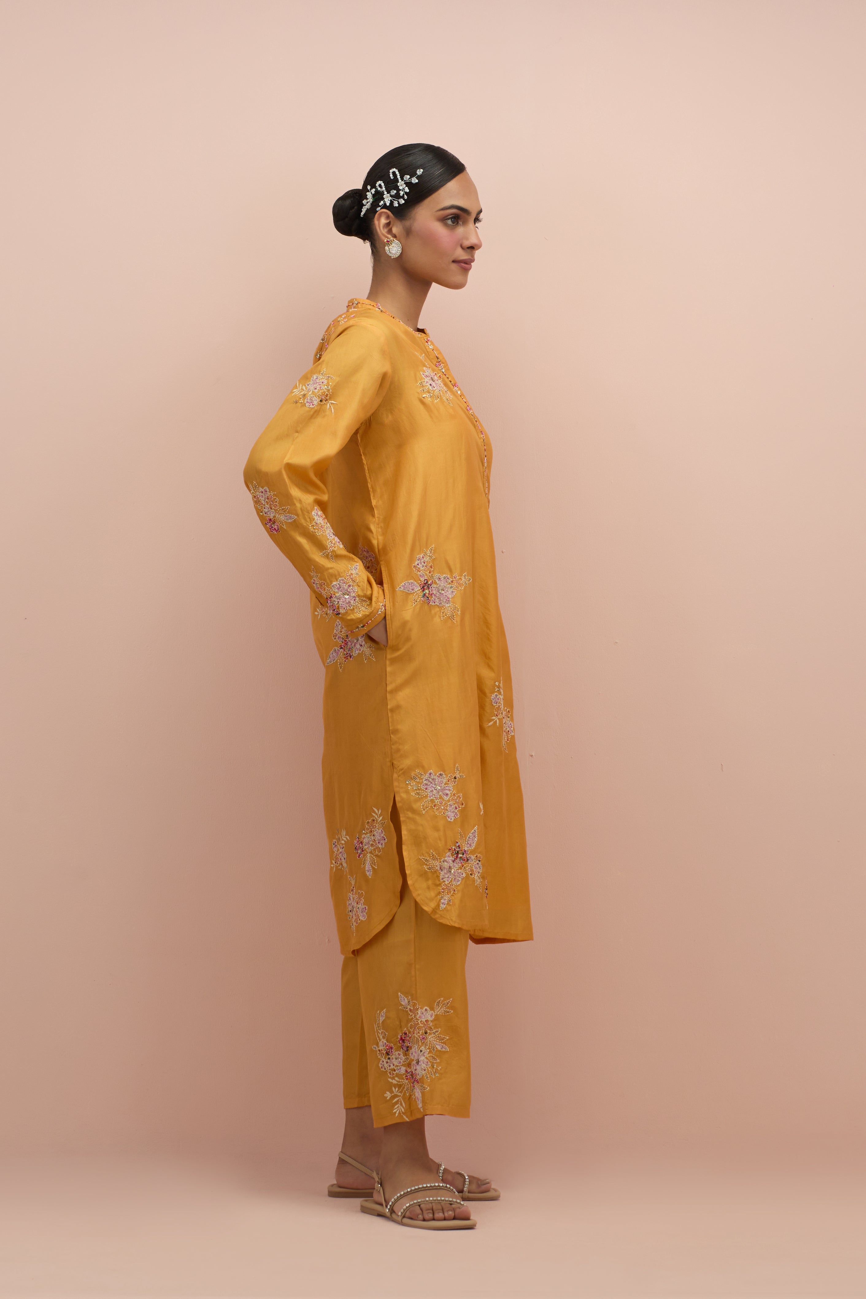 Amber silk short shirt kurta with all-over hand block printed appliqué, highlighted with sequins and multi colored beads, paired with amber silk ankle length straight pants with hand block printed appliqué motifs at the sides.