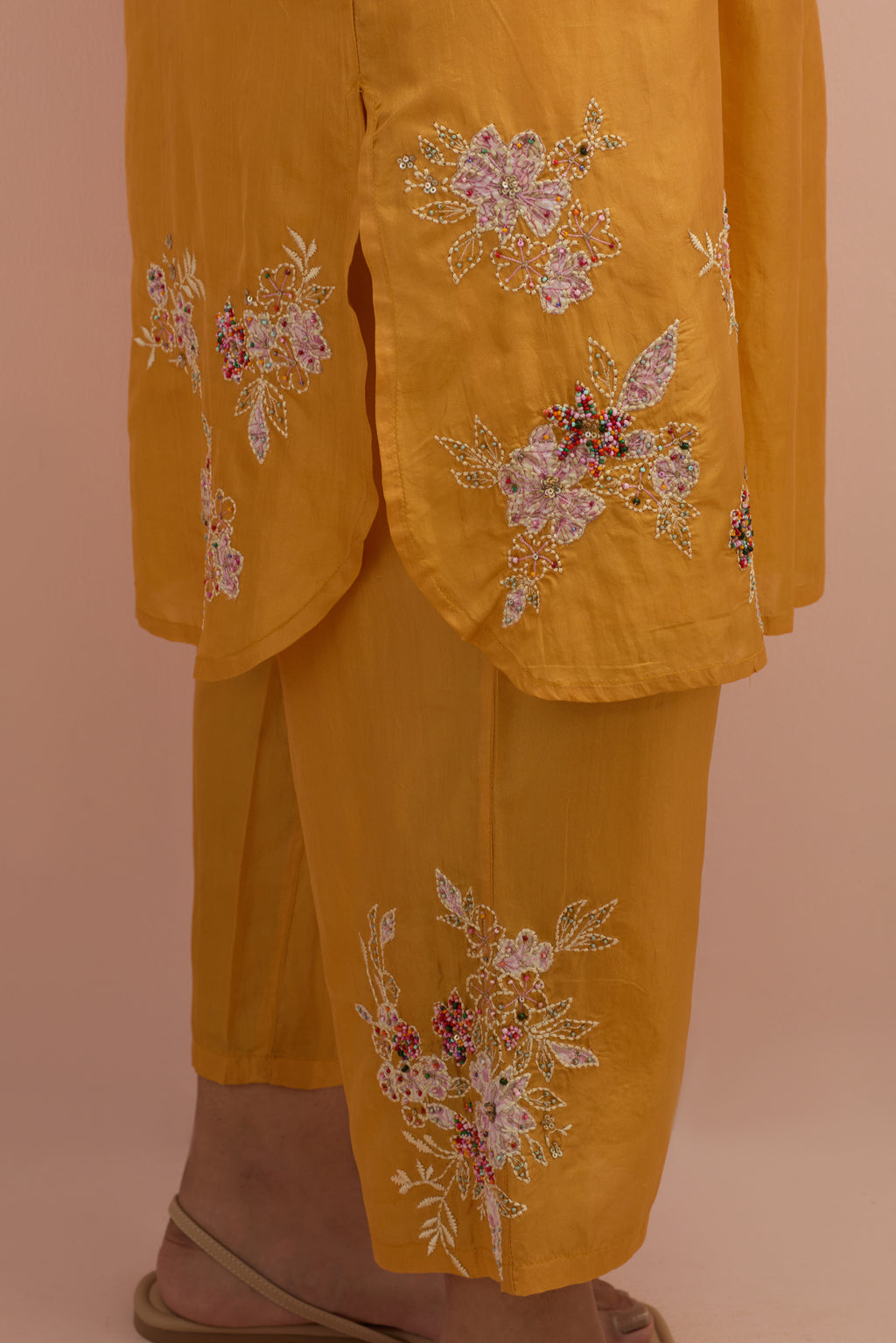 Amber silk short shirt kurta with all-over hand block printed appliqué, highlighted with sequins and multi colored beads, paired with amber silk ankle length straight pants with hand block printed appliqué motifs at the sides.