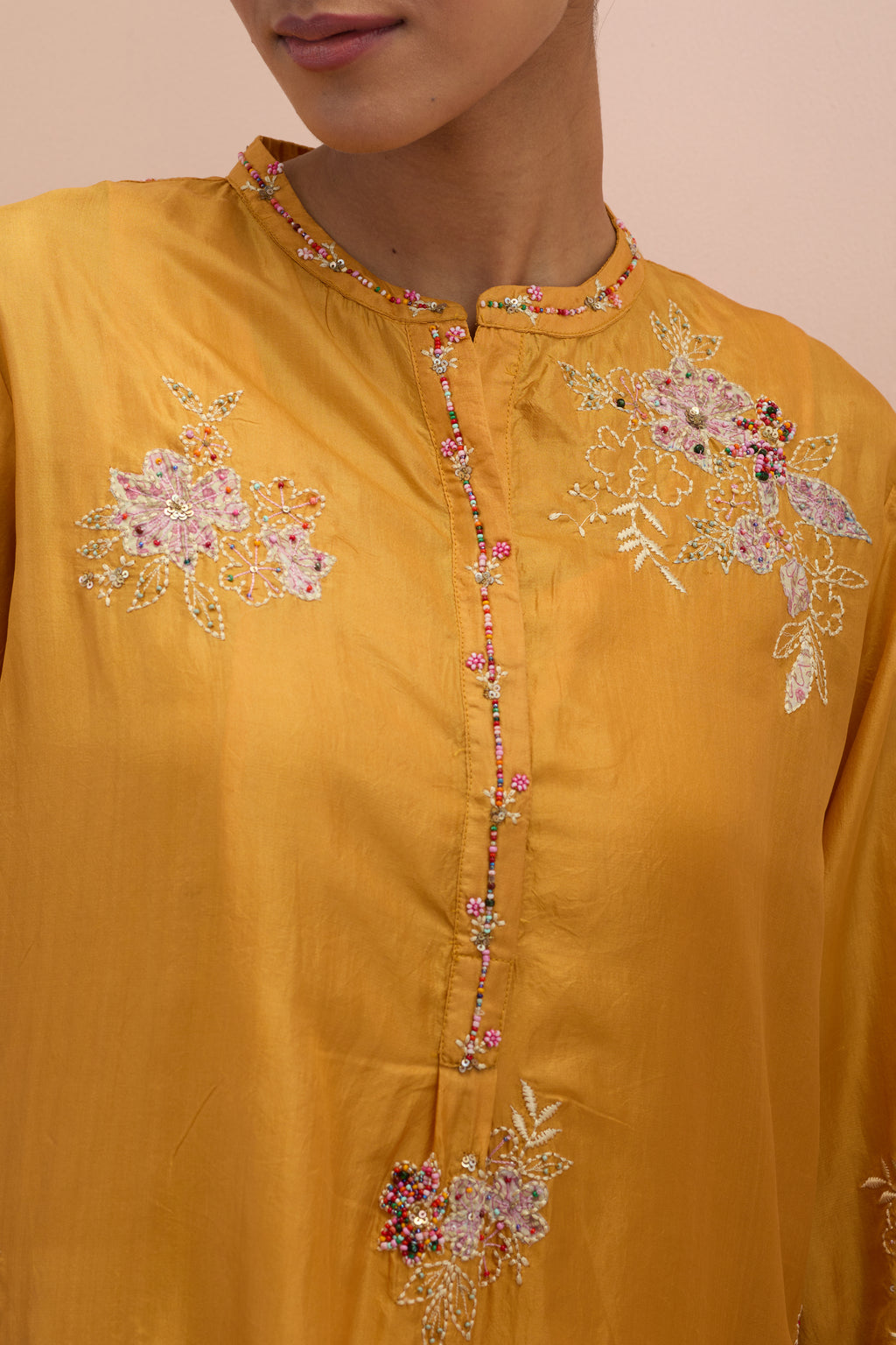 Amber silk short shirt kurta with all-over hand block printed appliqué, highlighted with sequins and multi colored beads, paired with amber silk ankle length straight pants with hand block printed appliqué motifs at the sides.