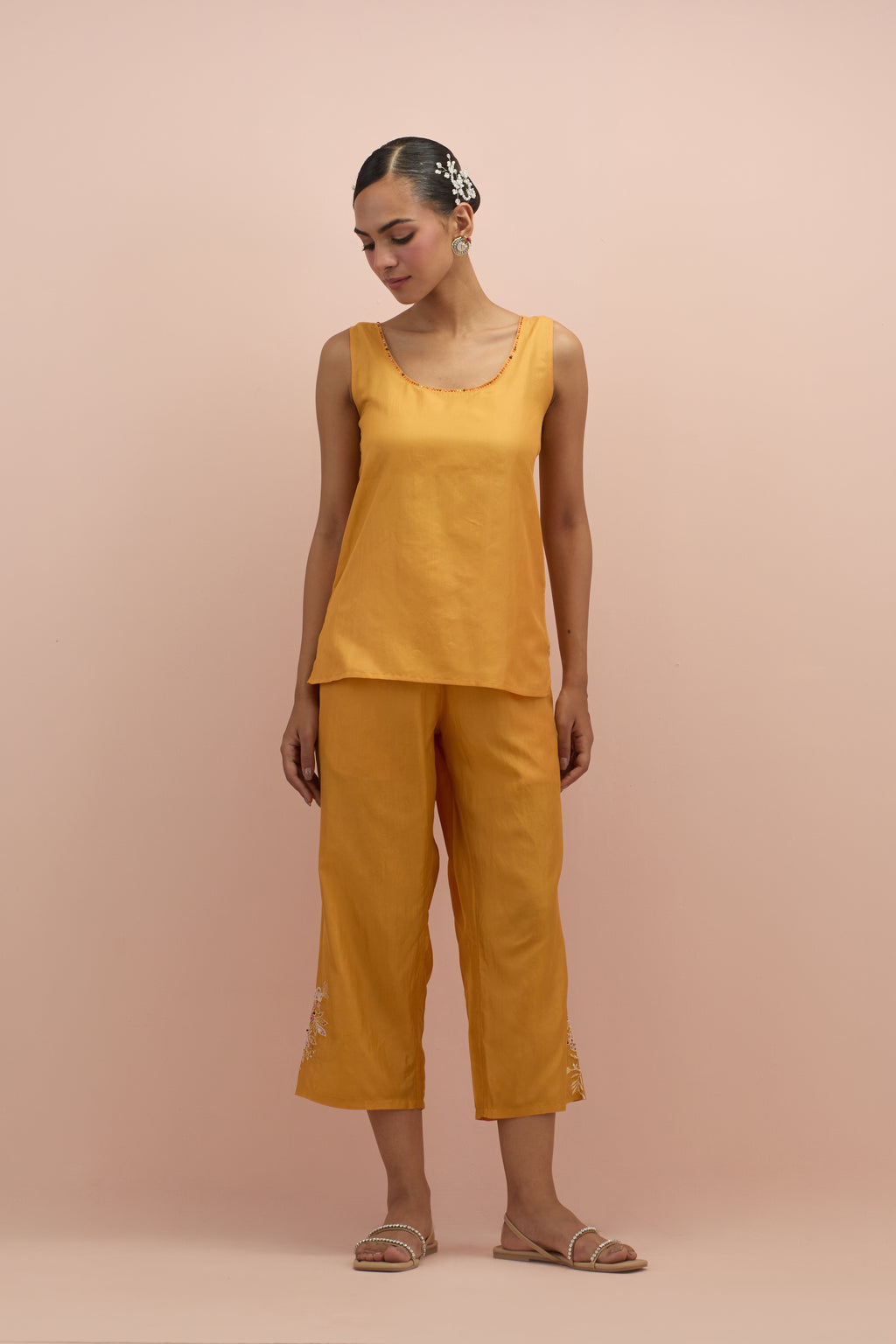 Amber silk short top with hand block printed appliqué motifs and delicate embroidered flowers, highlighted with sequins and multi-colored beads, paired with amber silk ankle length straight pants.