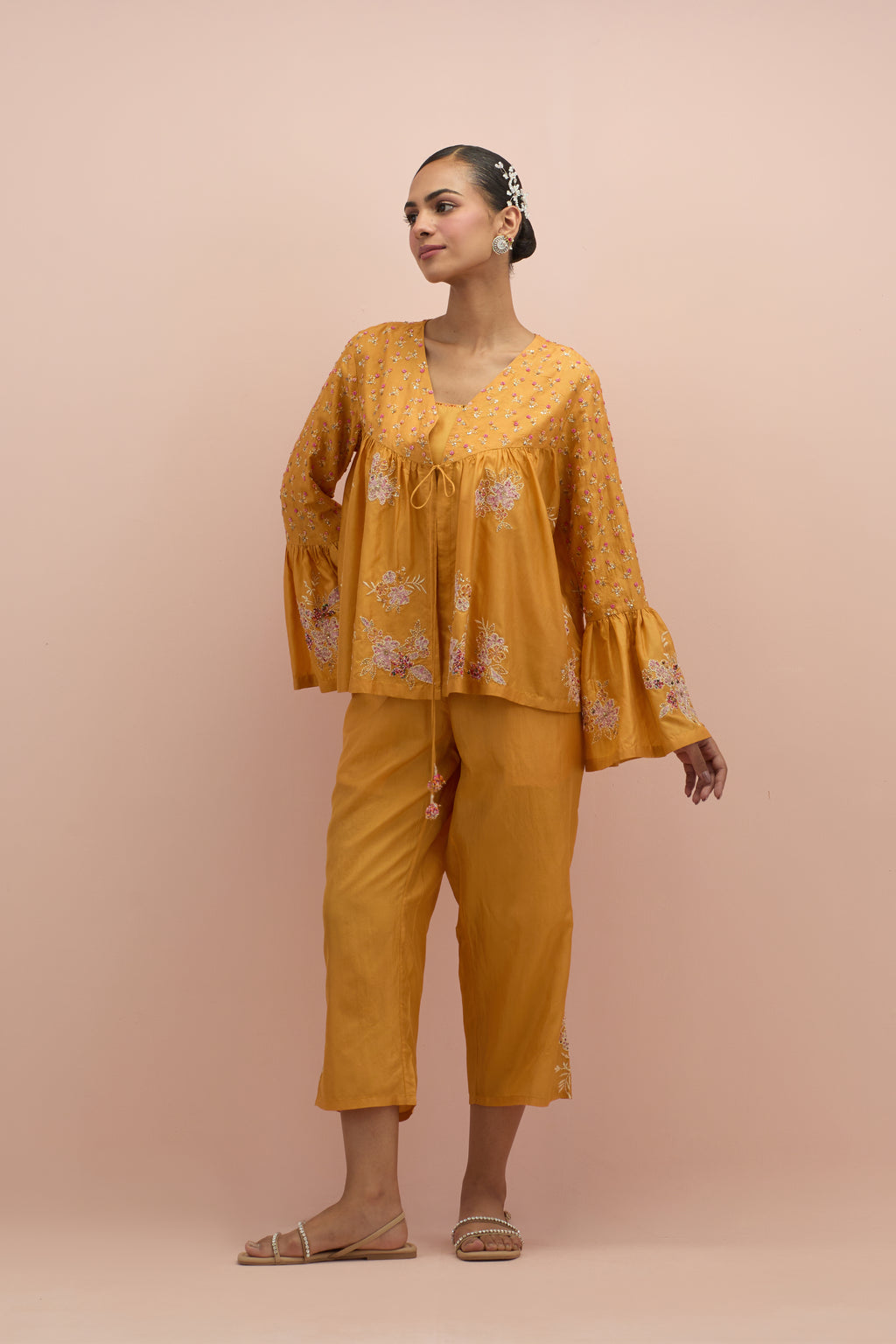 Amber silk short top with hand block printed appliqué motifs and delicate embroidered flowers, highlighted with sequins and multi-colored beads, paired with amber silk ankle length straight pants.