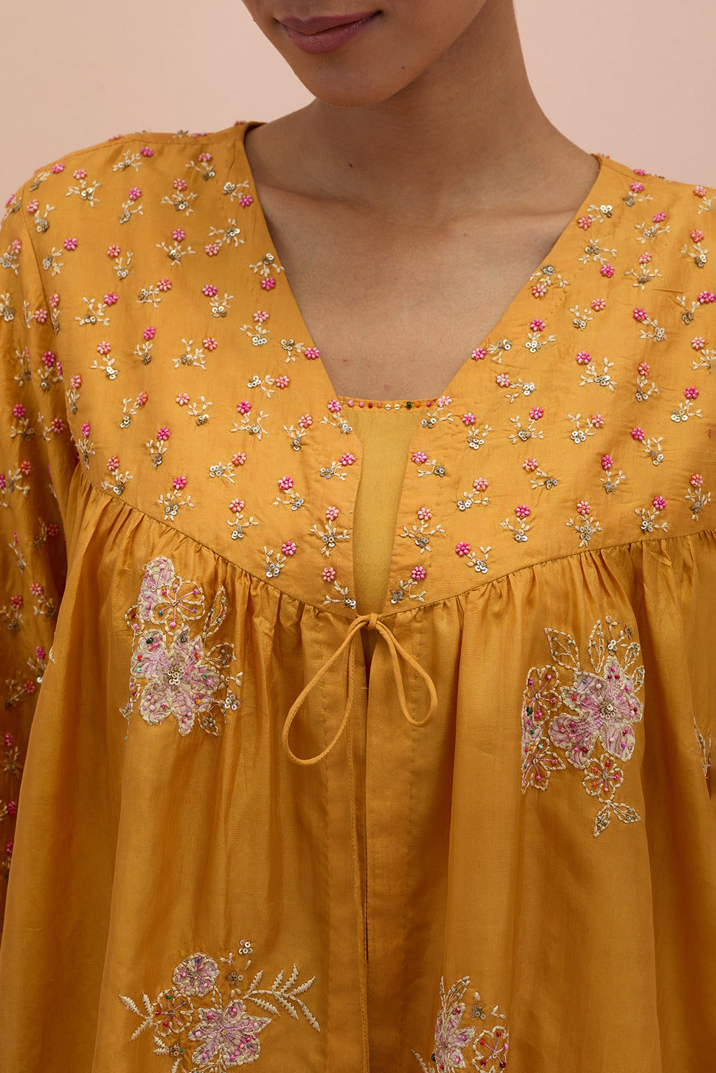 Amber silk short top with hand block printed appliqué motifs and delicate embroidered flowers, highlighted with sequins and multi-colored beads, paired with amber silk ankle length straight pants.