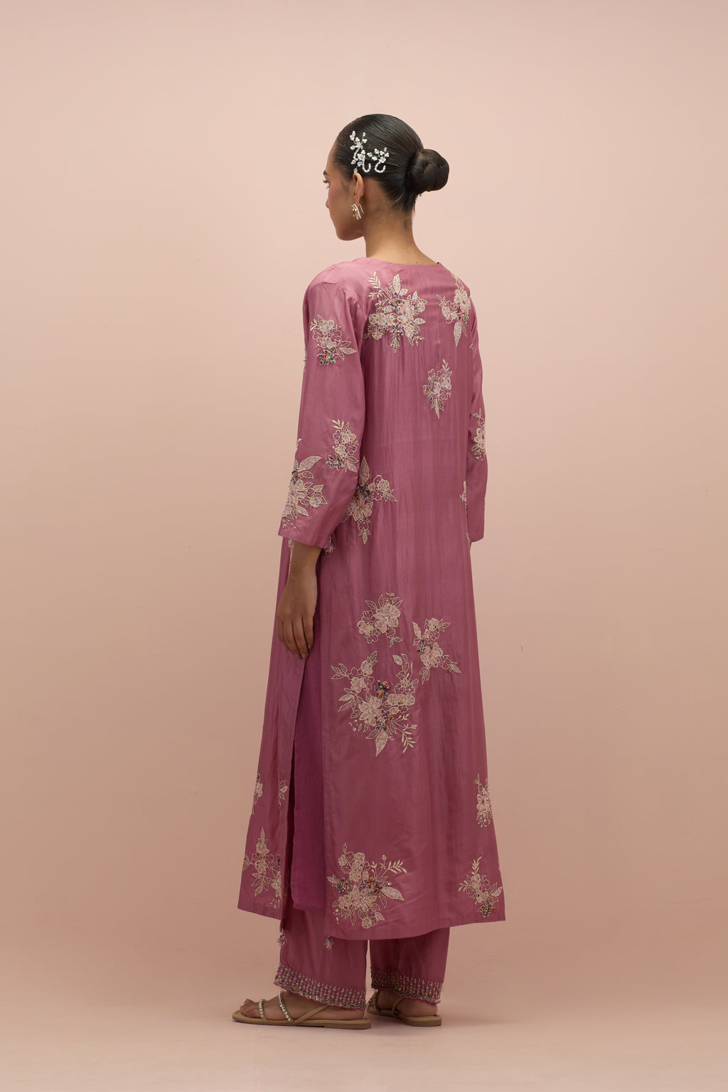 Salmon pink silk straight kurta set with randomly placed hand block printed appliquéd flowers, highlighted with sequins and multi-colored beads.