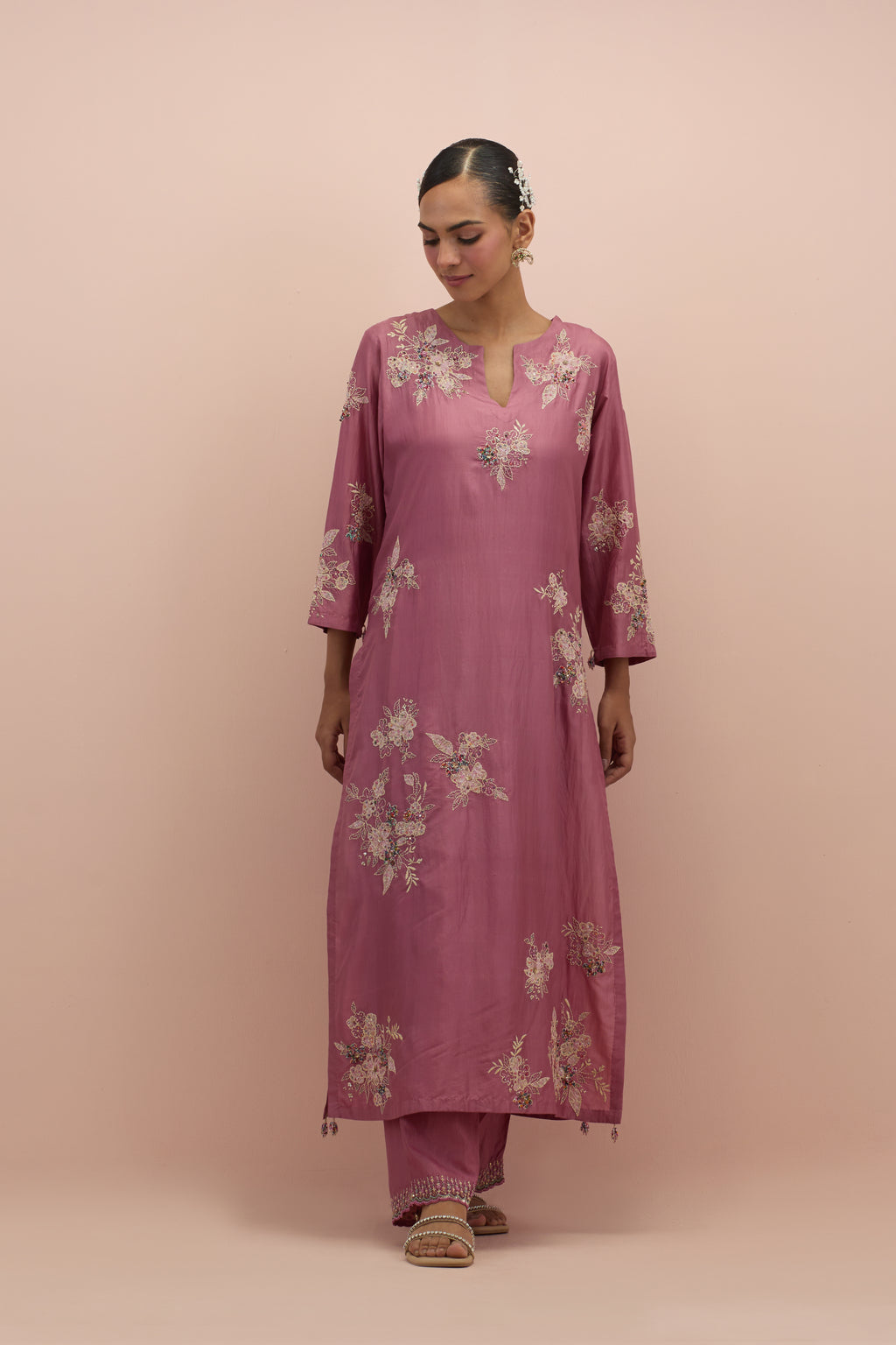 Salmon pink silk straight kurta set with randomly placed hand block printed appliquéd flowers, highlighted with sequins and multi-colored beads.