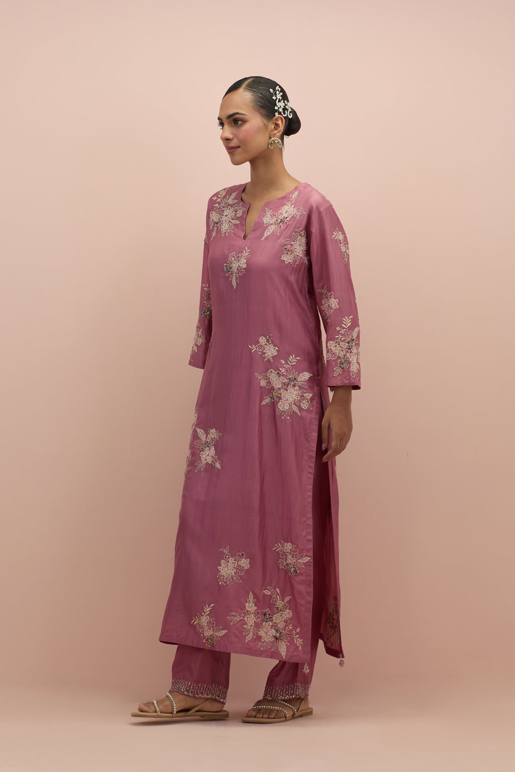 Salmon pink silk straight kurta set with randomly placed hand block printed appliquéd flowers, highlighted with sequins and multi-colored beads.