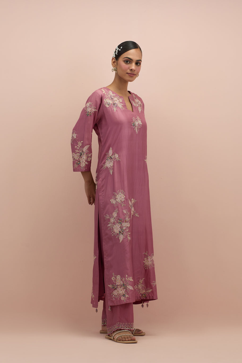 Salmon pink silk straight kurta set with randomly placed hand block printed appliquéd flowers, highlighted with sequins and multi-colored beads.