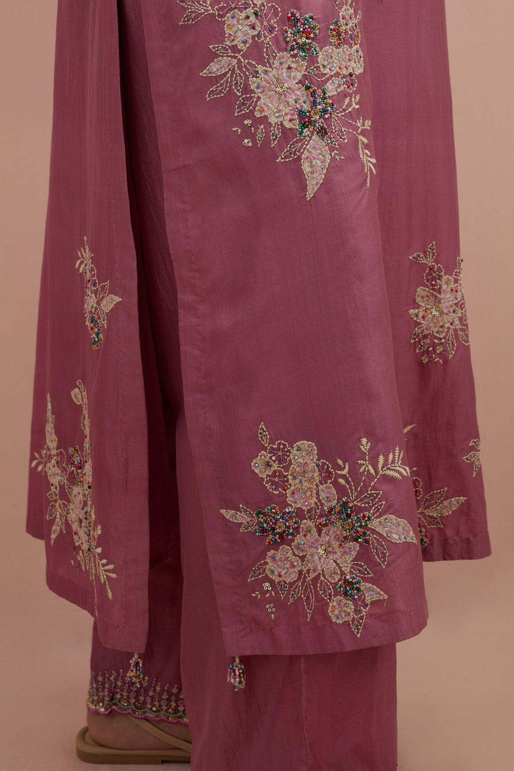 Salmon pink silk straight kurta set with randomly placed hand block printed appliquéd flowers, highlighted with sequins and multi-colored beads.