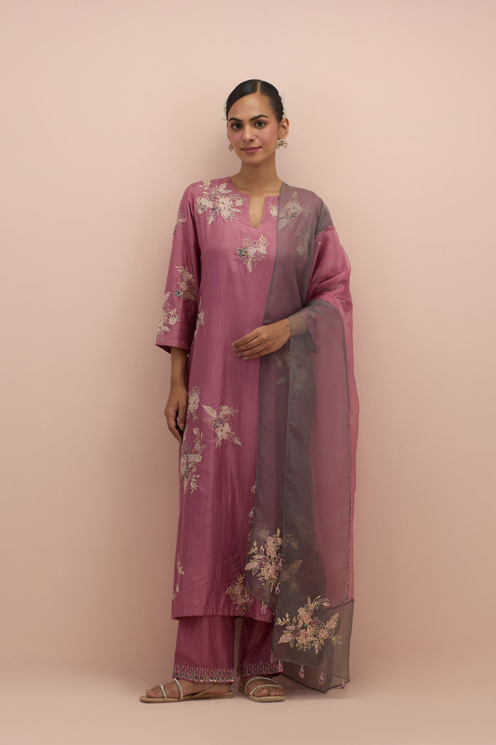 Salmon pink silk straight kurta set with randomly placed hand block printed appliquéd flowers, highlighted with sequins and multi-colored beads.