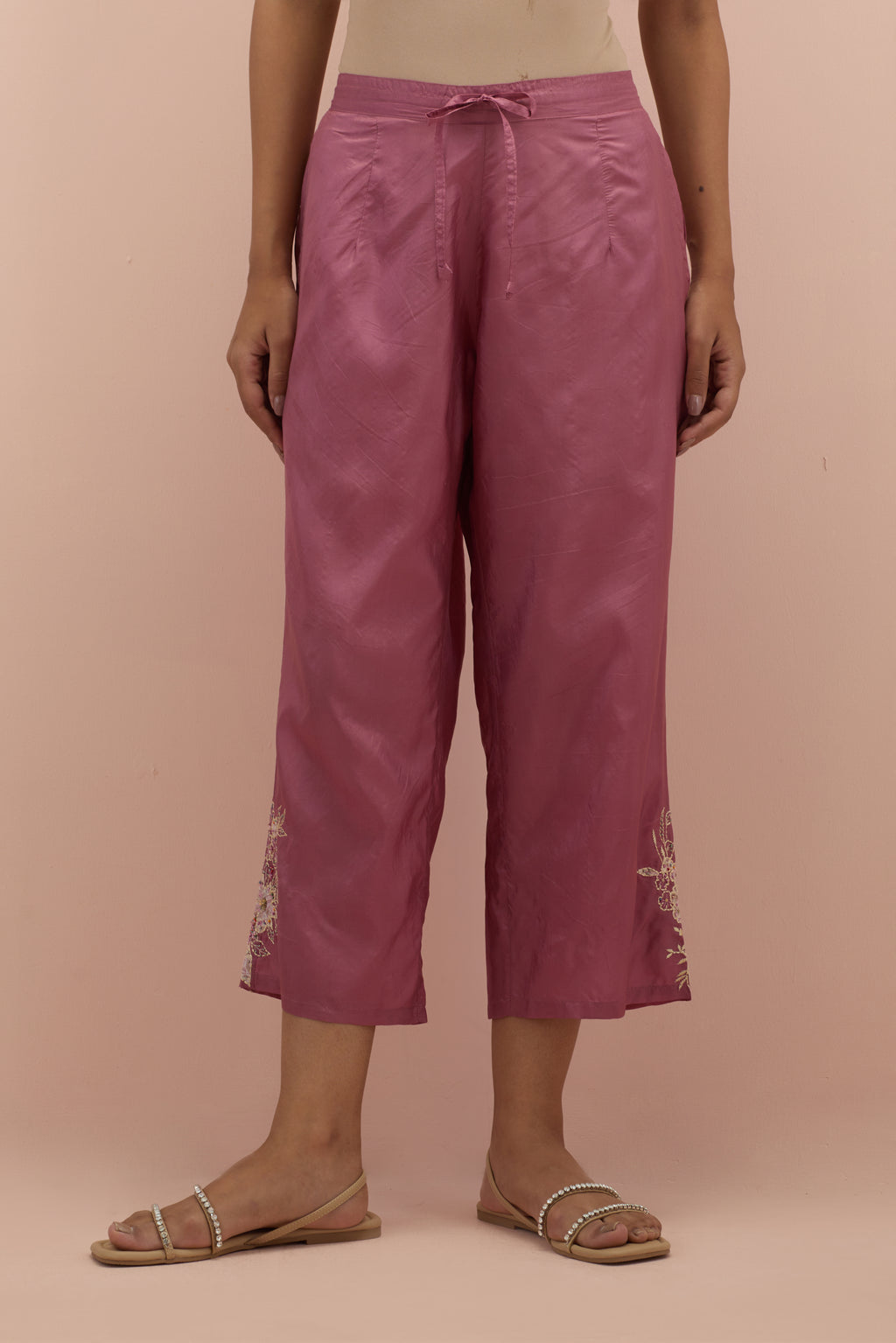 Salmon pink silk ankle length straight pants with hand block printed appliqué motifs at the sides, highlighted with sequins and multi-colored beads.