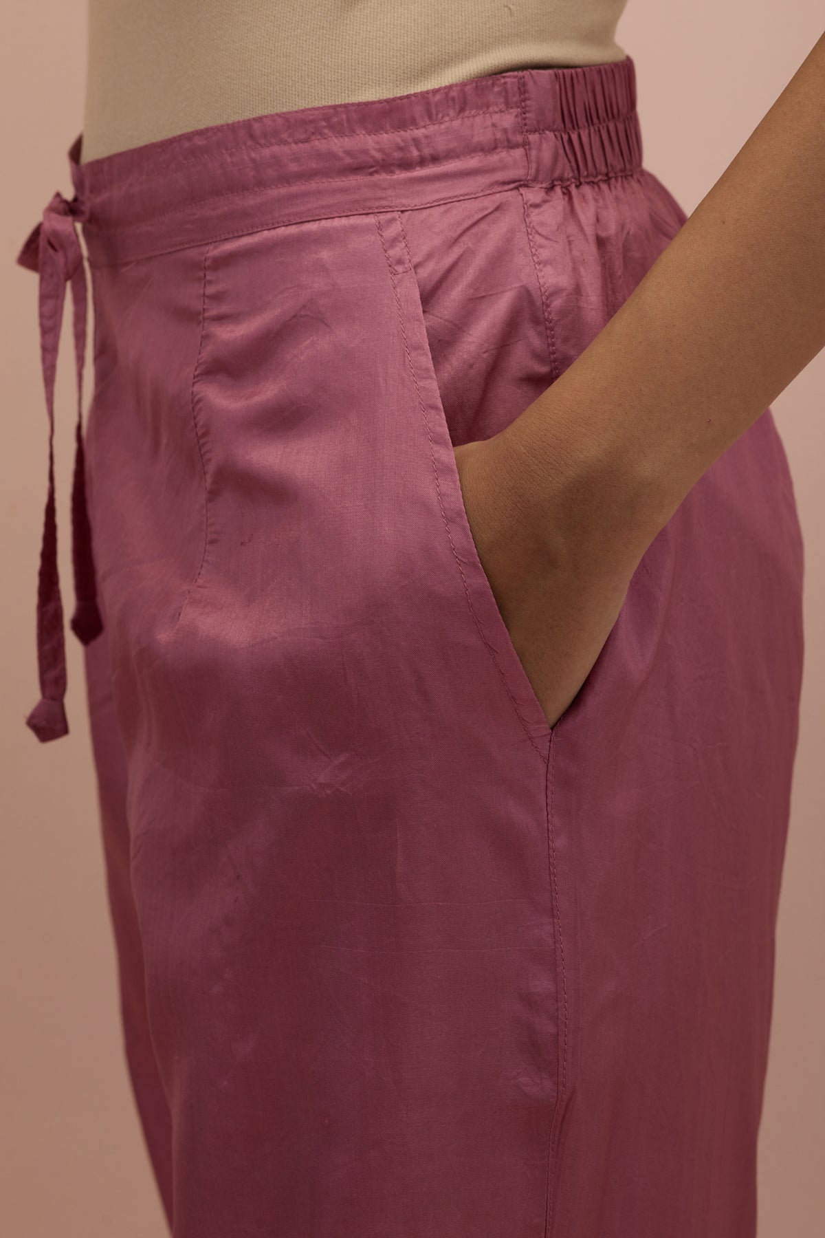 Salmon pink silk ankle length straight pants with hand block printed appliqué motifs at the sides, highlighted with sequins and multi-colored beads.