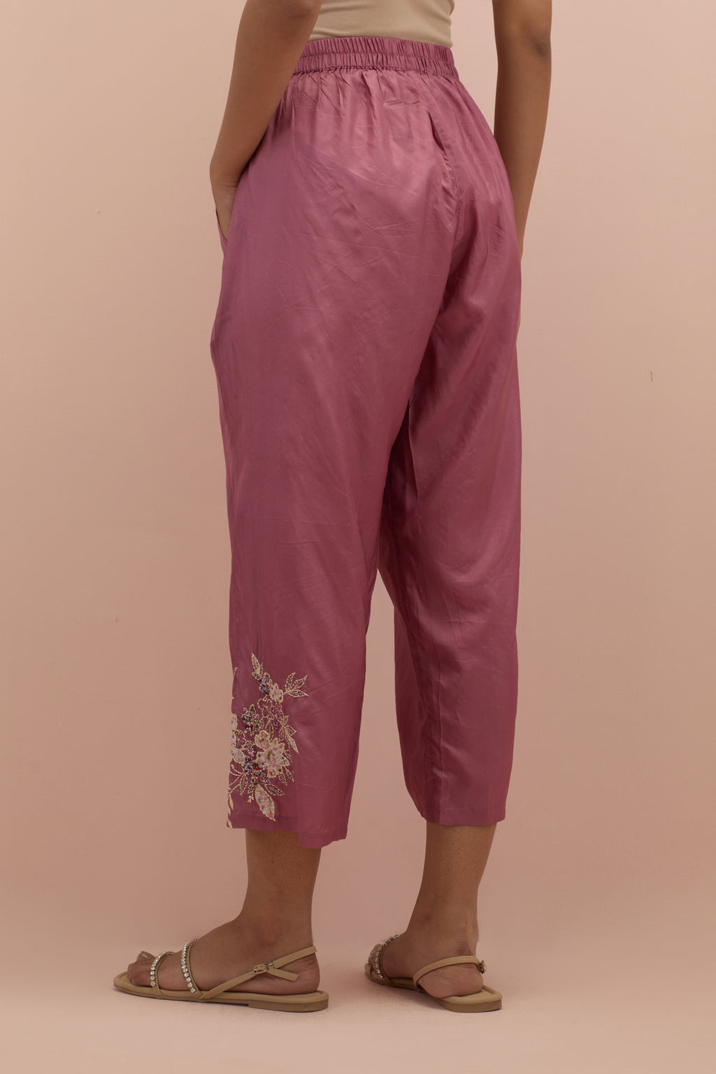 Salmon pink silk ankle length straight pants with hand block printed appliqué motifs at the sides, highlighted with sequins and multi-colored beads.