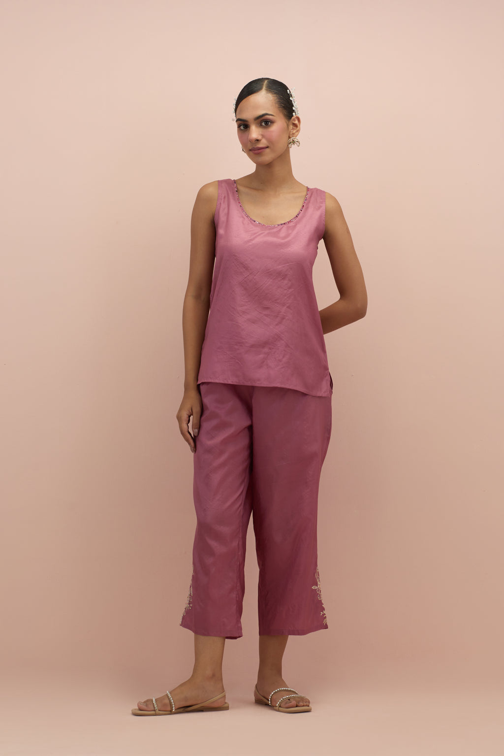 Salmon pink silk short top with hand block printed appliqué motifs and delicate embroidered flowers, highlighted with sequins and multi-colored beads, paired with salmon pink silk ankle length straight pants.