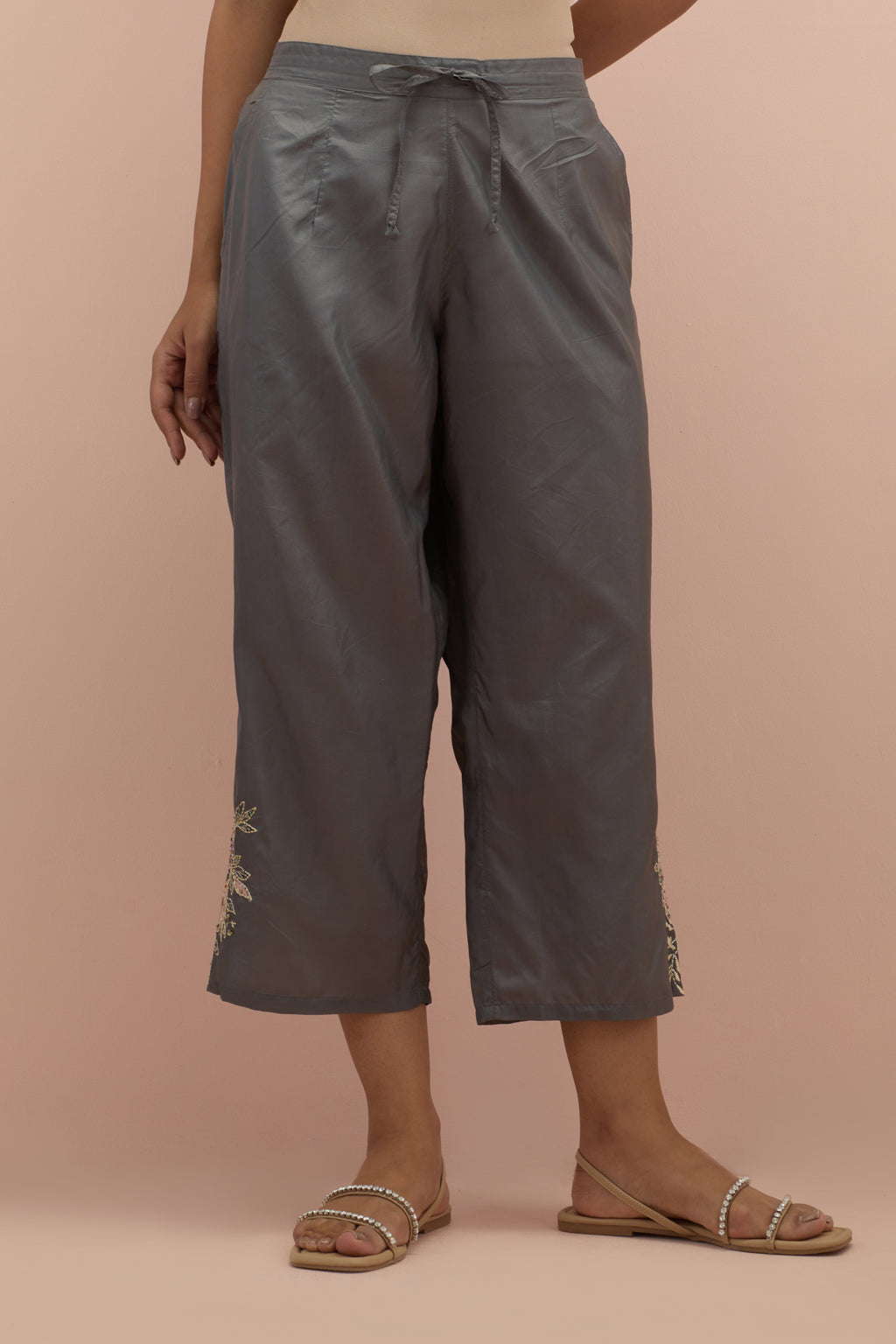 Iron grey silk ankle length straight pants with hand block printed appliqué motifs at the sides, highlighted with sequins and multi-colored beads.