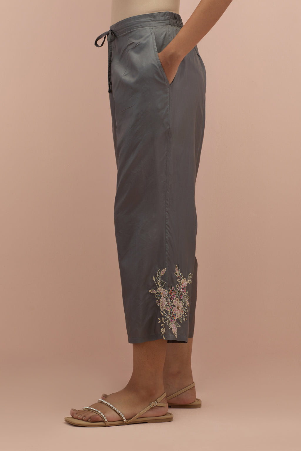 Iron grey silk ankle length straight pants with hand block printed appliqué motifs at the sides, highlighted with sequins and multi-colored beads.