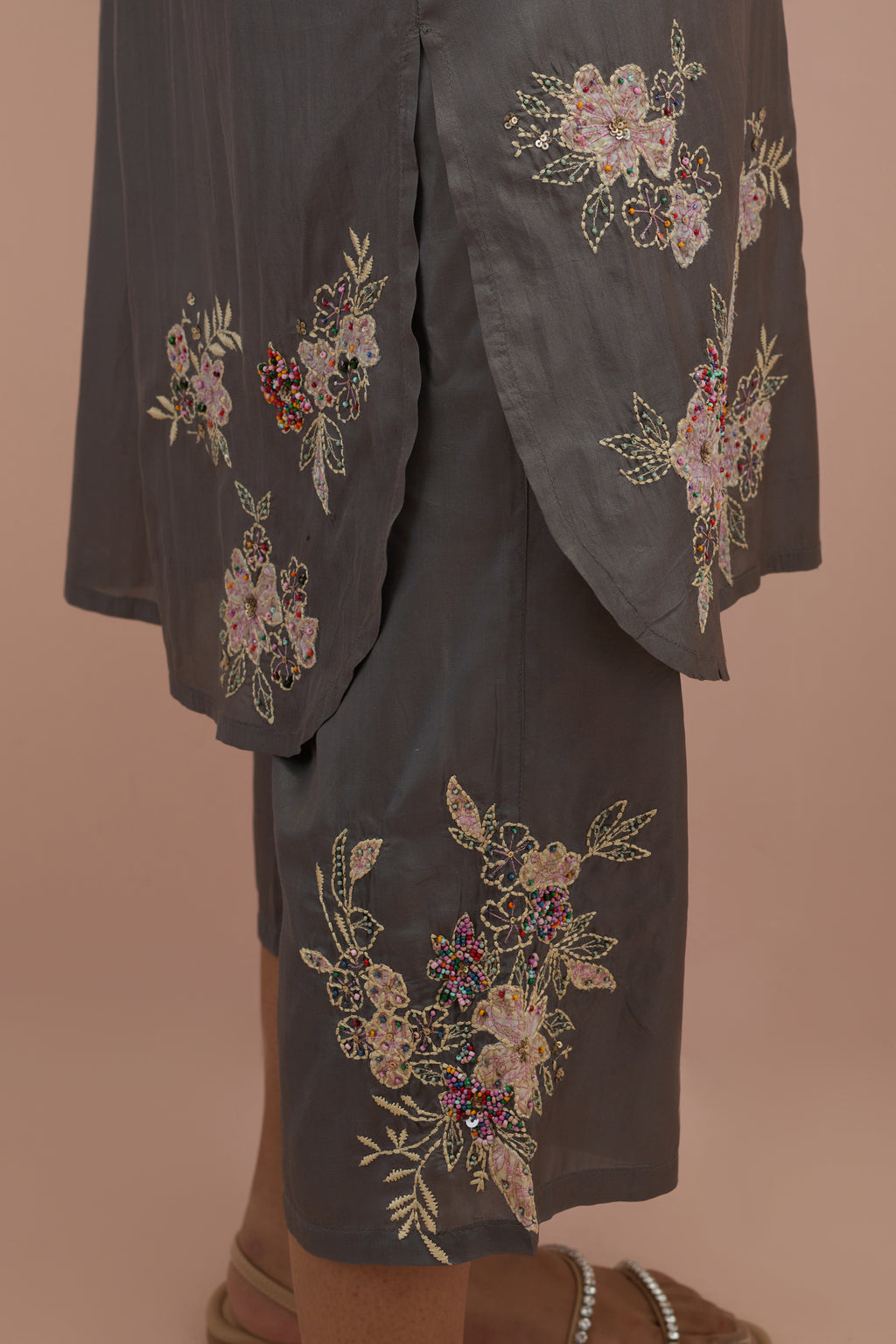 Iron grey silk short shirt kurta with all-over hand block printed appliqué, highlighted with sequins and multi colored beads, paired with iron grey silk ankle length straight pants with hand block printed appliqué motifs at the sides.