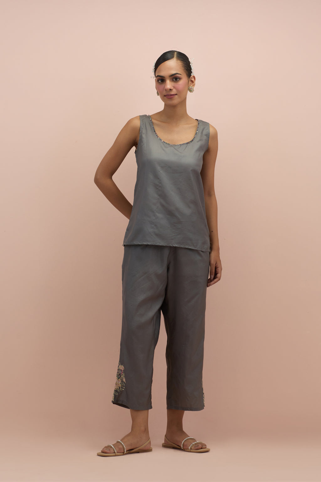 Iron grey silk short top with hand block printed appliqué motifs and delicate embroidered flowers, highlighted with sequins and multi-colored beads, paired with iron grey silk ankle length straight pants.