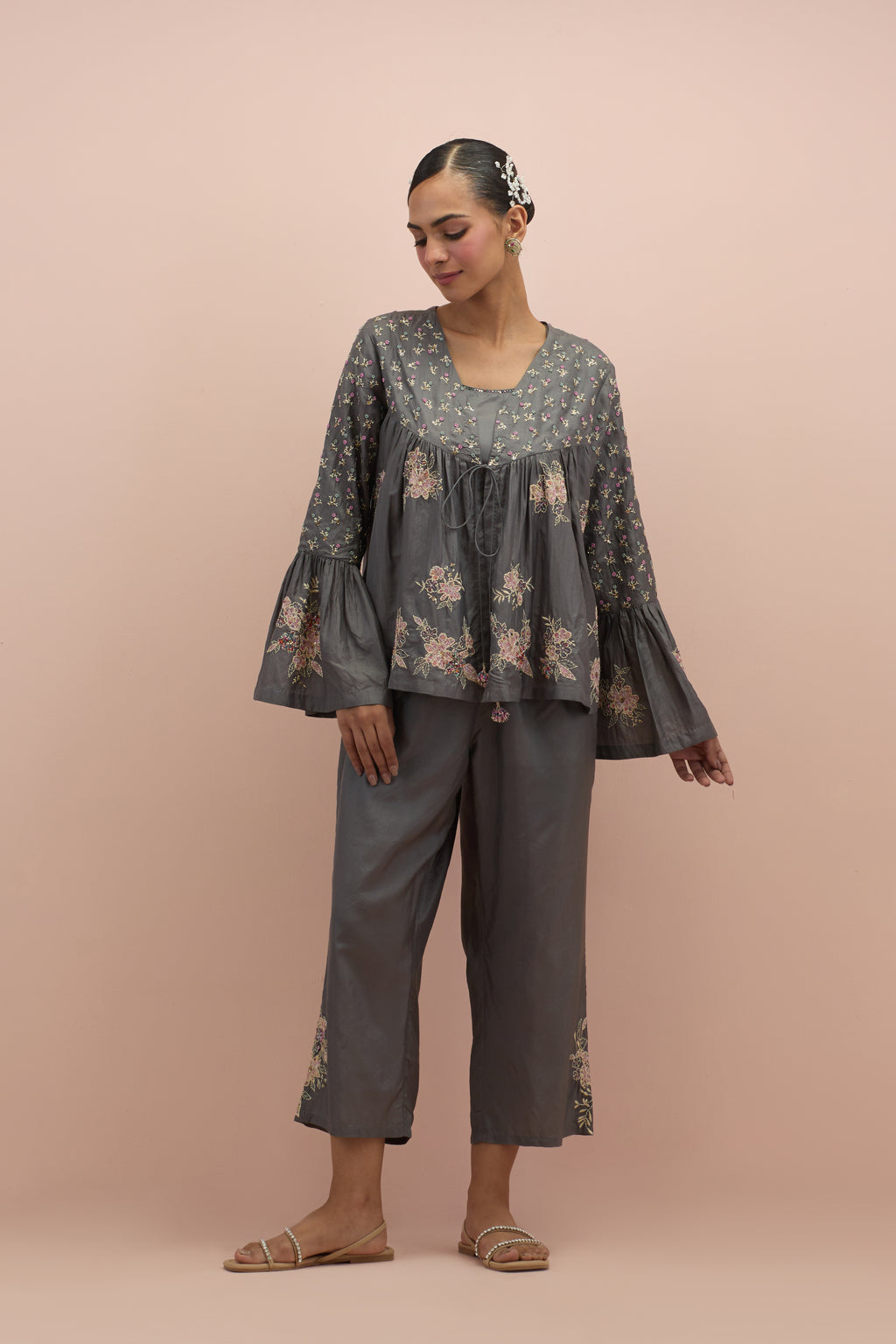 Iron grey silk short top with hand block printed appliqué motifs and delicate embroidered flowers, highlighted with sequins and multi-colored beads, paired with iron grey silk ankle length straight pants.