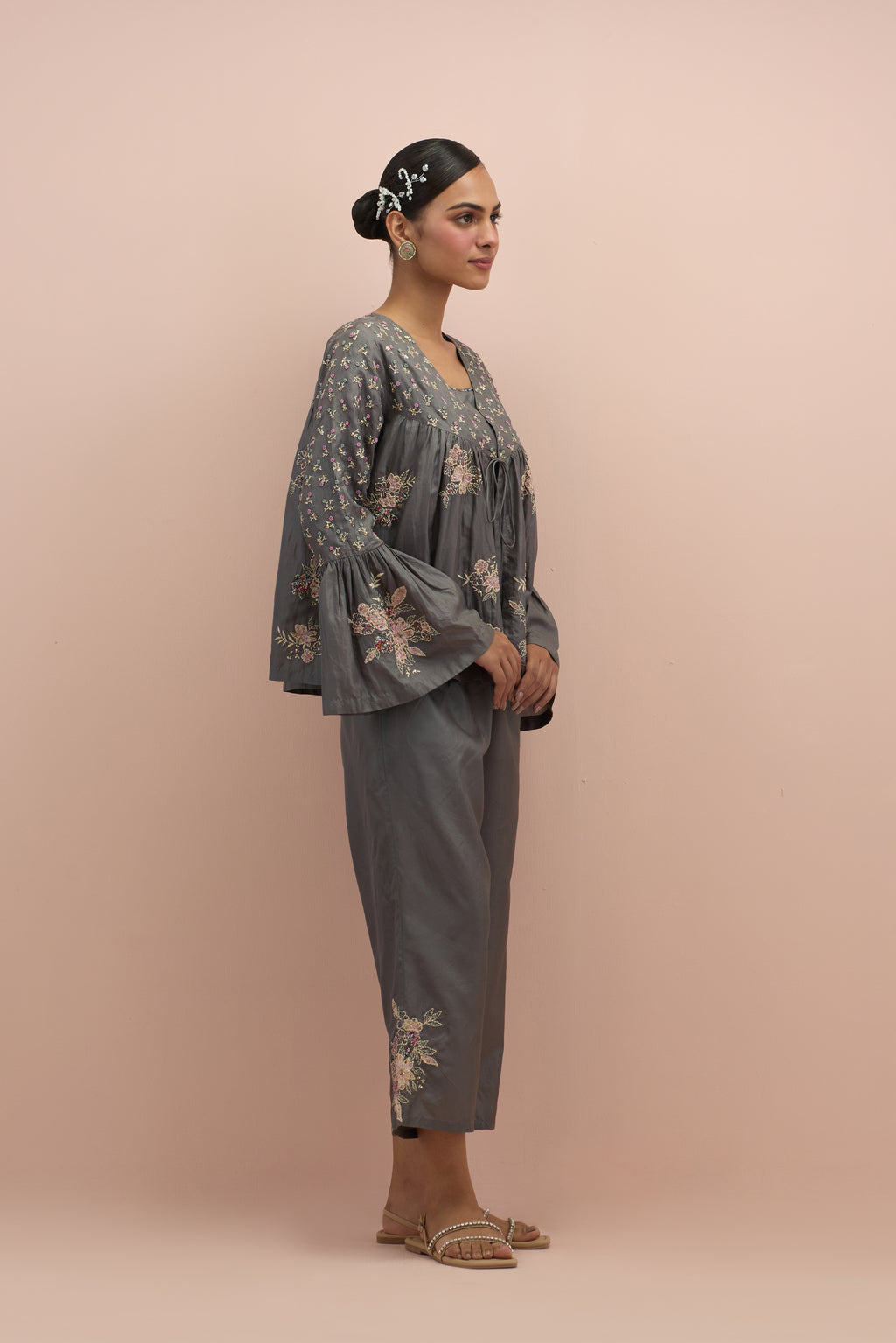 Iron grey silk short top with hand block printed appliqué motifs and delicate embroidered flowers, highlighted with sequins and multi-colored beads, paired with iron grey silk ankle length straight pants.