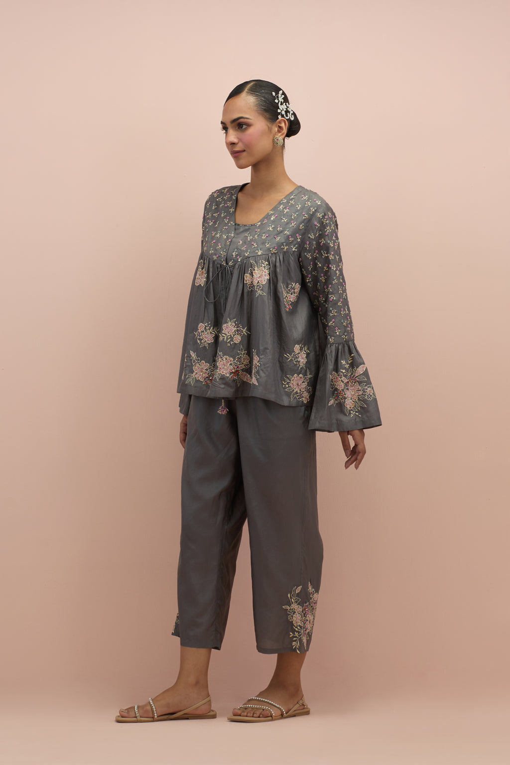 Iron grey silk short top with hand block printed appliqué motifs and delicate embroidered flowers, highlighted with sequins and multi-colored beads, paired with iron grey silk ankle length straight pants.