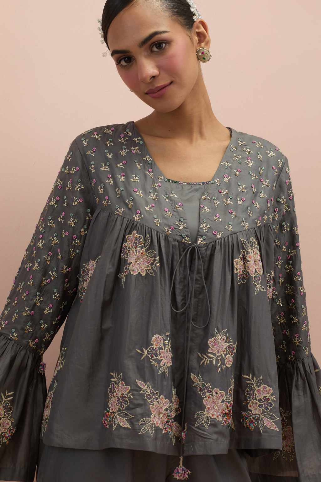 Iron grey silk short top with hand block printed appliqué motifs and delicate embroidered flowers, highlighted with sequins and multi-colored beads, paired with iron grey silk ankle length straight pants.