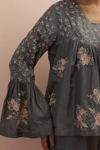 Iron grey silk short top with hand block printed appliqué motifs and delicate embroidered flowers, highlighted with sequins and multi-colored beads, paired with iron grey silk ankle length straight pants.