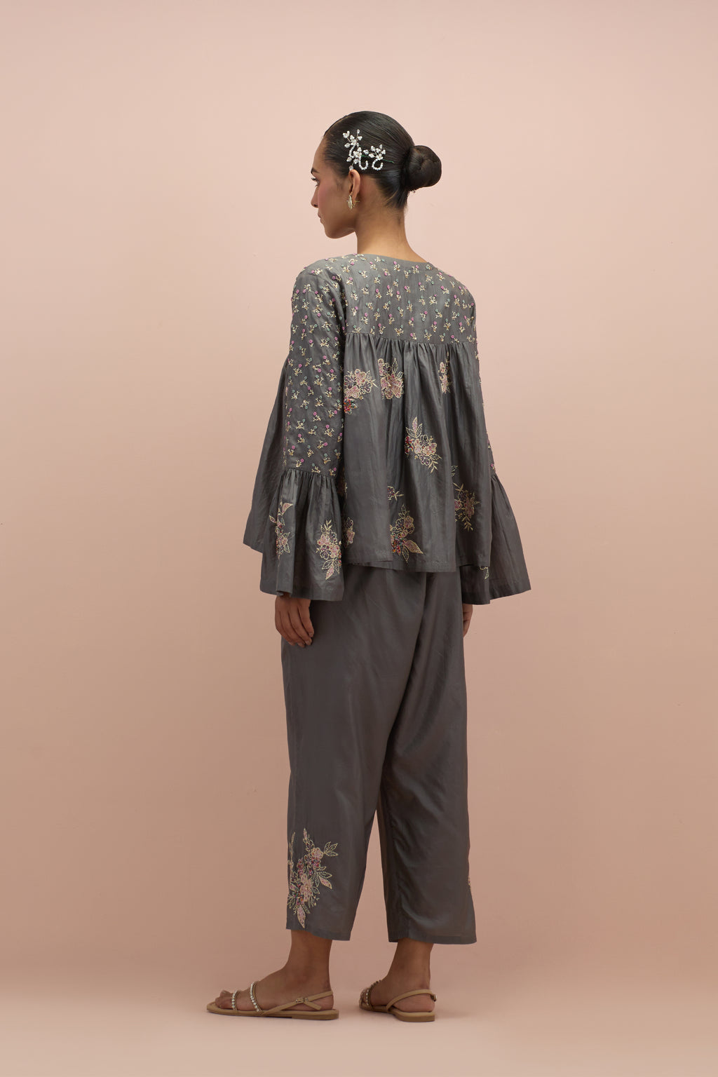 Iron grey silk short top with hand block printed appliqué motifs and delicate embroidered flowers, highlighted with sequins and multi-colored beads, paired with iron grey silk ankle length straight pants.