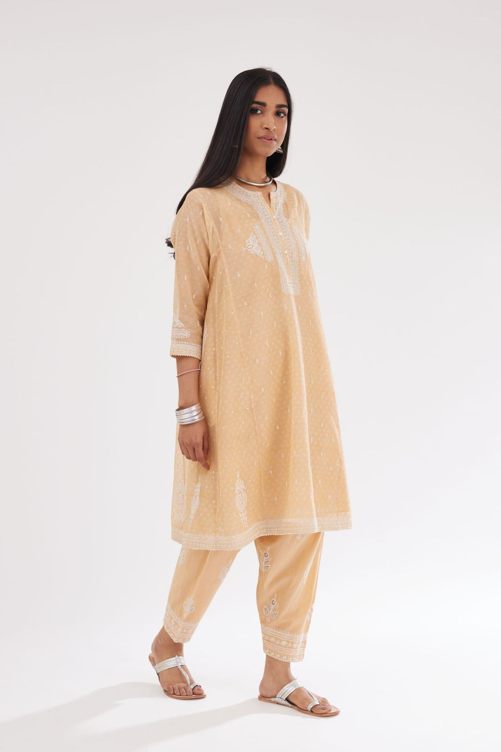 Peach cotton chanderi hand block printed short kalidar phiran style kurta with button placket neckline and dori and silk thraed embroidery all over.