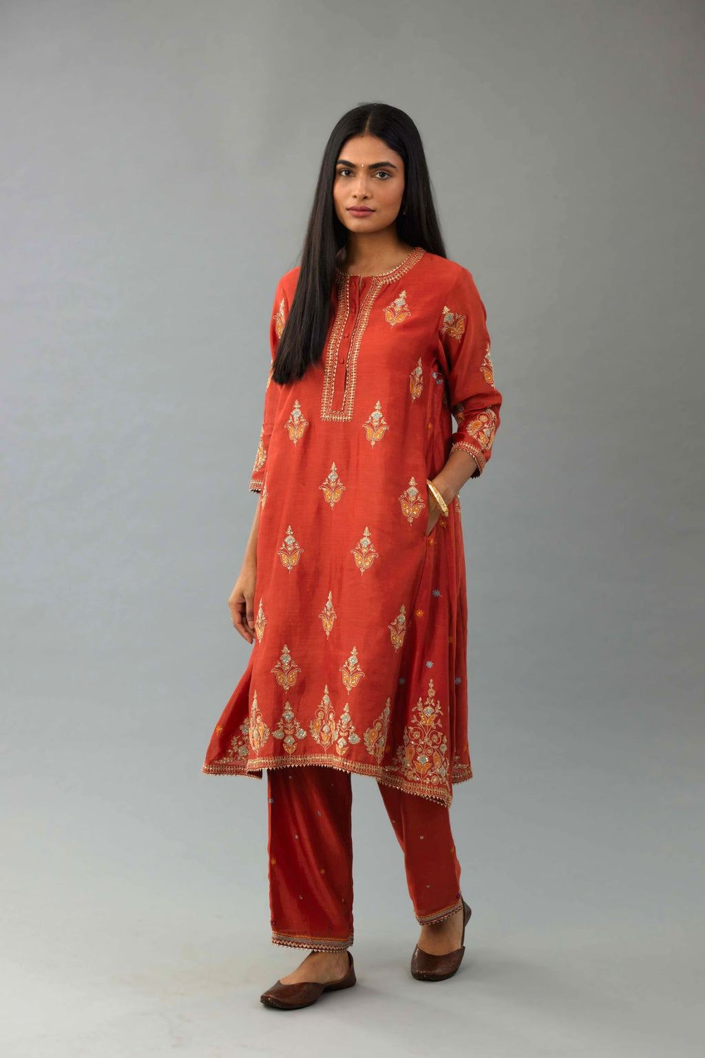 Rust silk chanderi A-line short kurta set with dori and contrast silk thread embroidery, highlighted with gold sequins work.