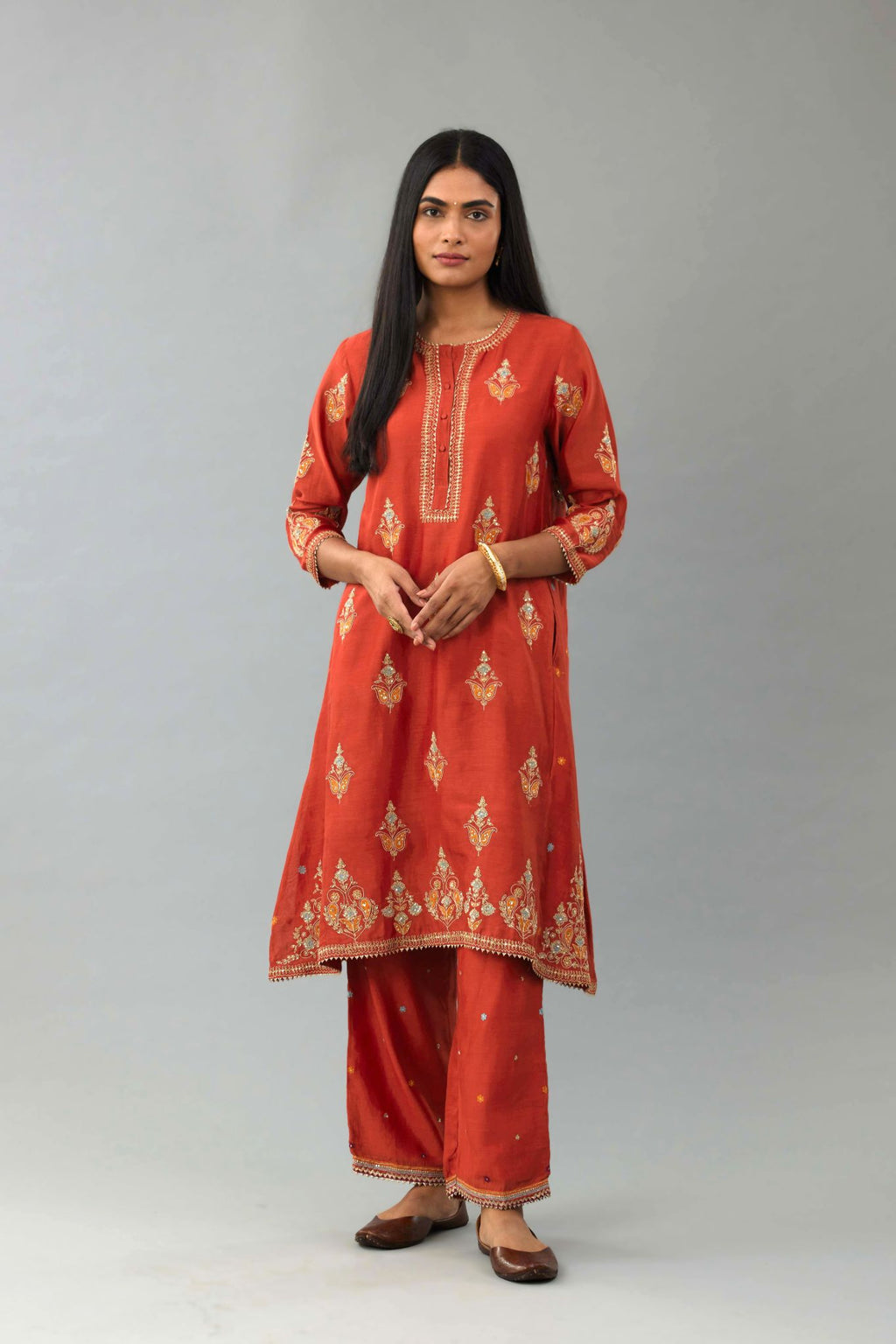 Rust silk chanderi A-line short kurta set with dori and contrast silk thread embroidery, highlighted with gold sequins work.