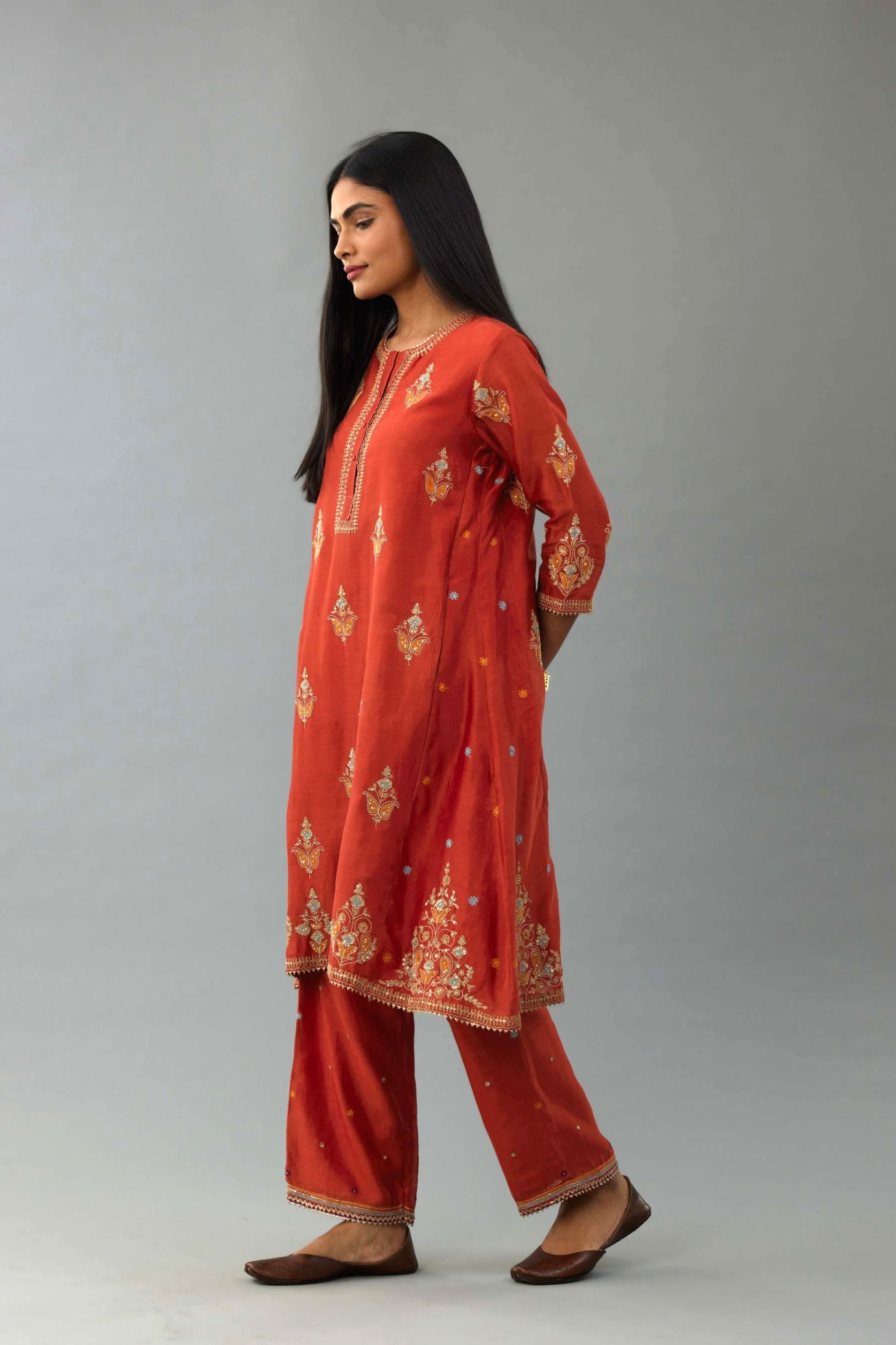 Rust silk chanderi A-line short kurta set with dori and contrast silk thread embroidery, highlighted with gold sequins work.