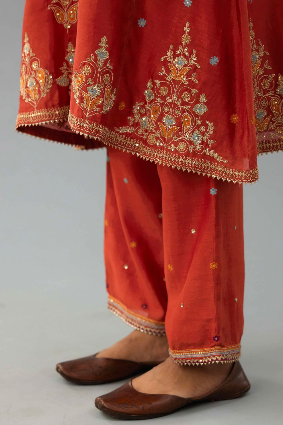 Rust silk chanderi A-line short kurta set with dori and contrast silk thread embroidery, highlighted with gold sequins work.