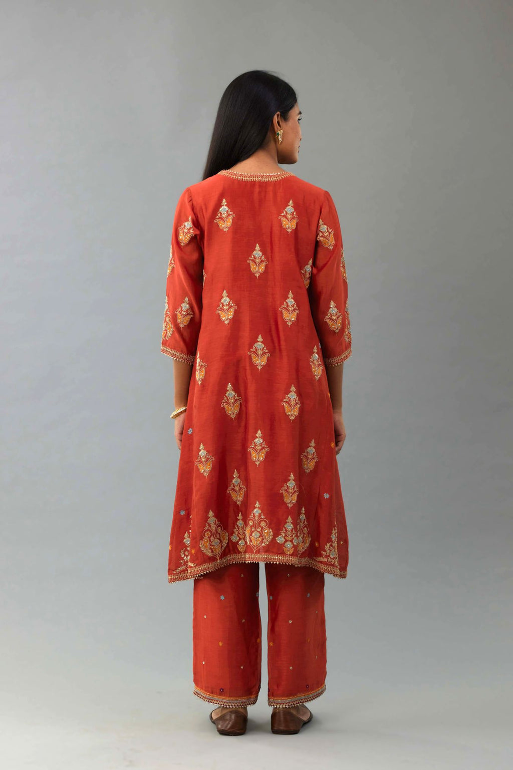 Rust silk chanderi A-line short kurta set with dori and contrast silk thread embroidery, highlighted with gold sequins work.
