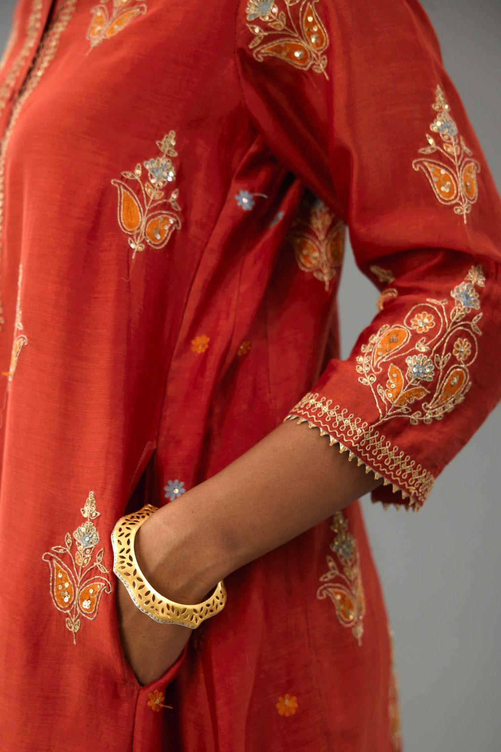 Rust silk chanderi A-line short kurta set with dori and contrast silk thread embroidery, highlighted with gold sequins work.