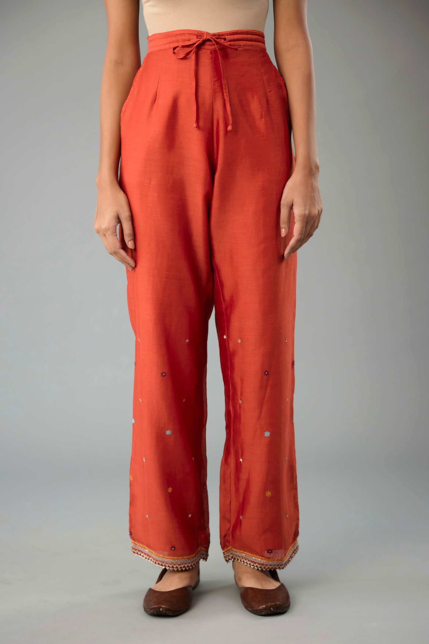 Rust silk chanderi straight pants with dori and contrast silk thread embroidery,  detailed with gold sequins work.