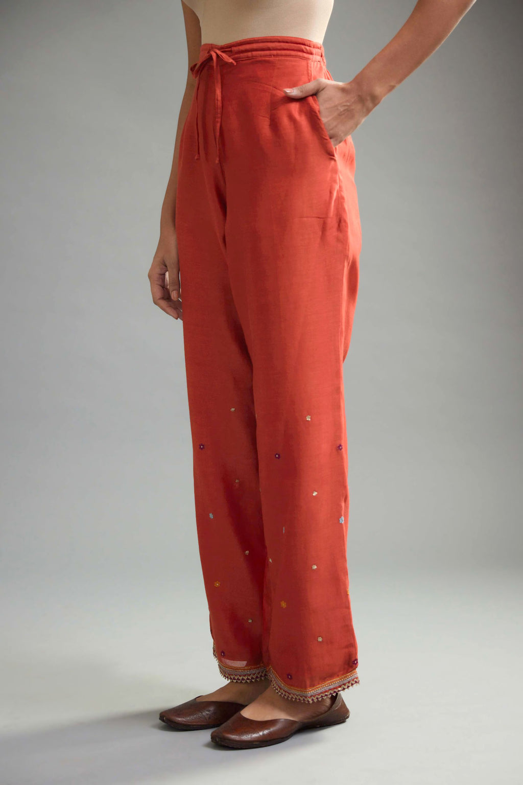 Rust silk chanderi straight pants with dori and contrast silk thread embroidery,  detailed with gold sequins work.
