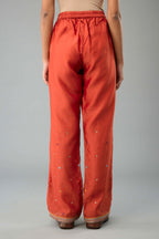 Rust silk chanderi straight pants with dori and contrast silk thread embroidery,  detailed with gold sequins work.