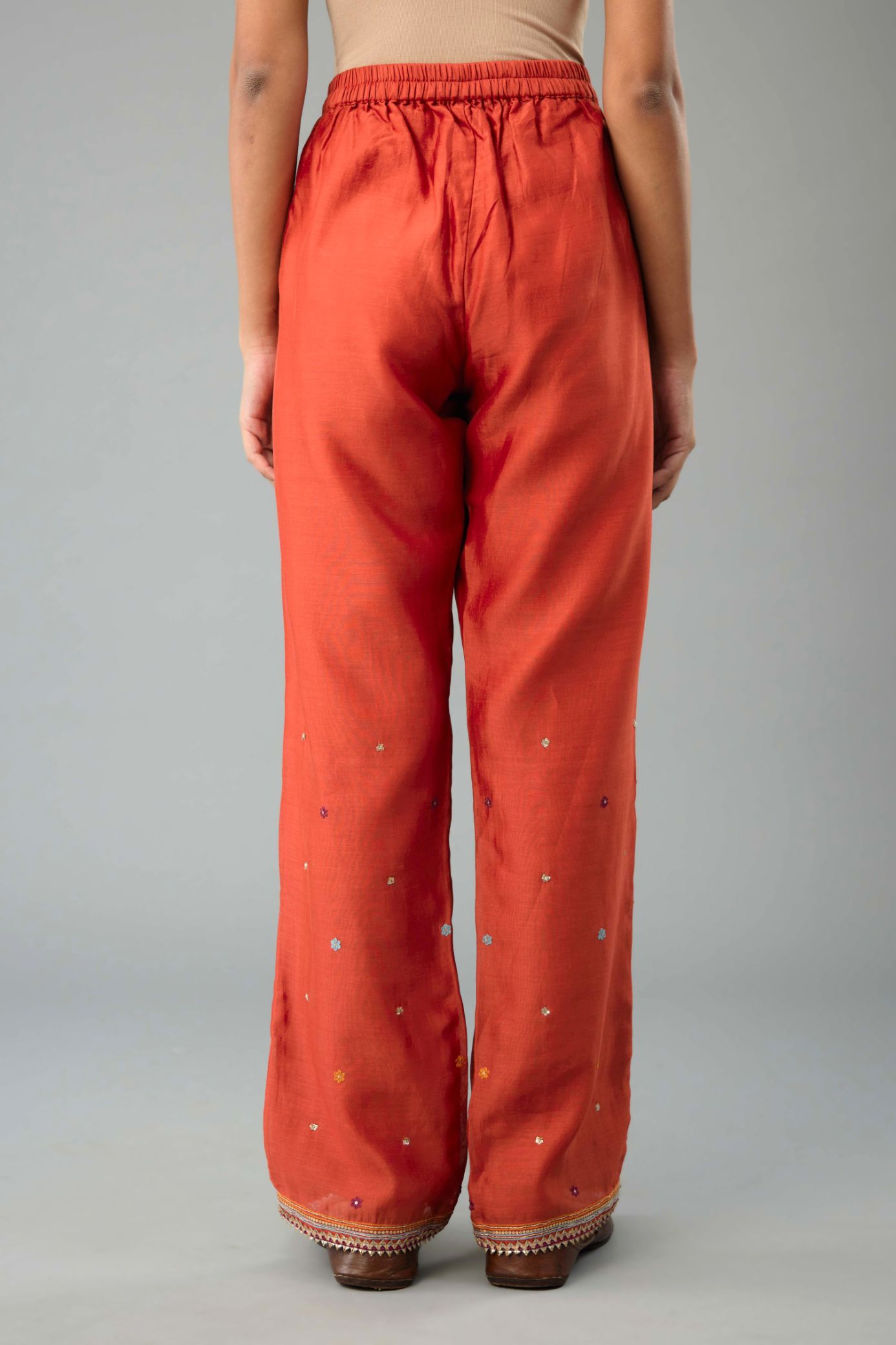 Rust silk chanderi straight pants with dori and contrast silk thread embroidery,  detailed with gold sequins work.