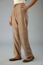 Taupe silk chanderi straight pants with dori and contrast silk thread embroidery,  detailed with gold sequins work.