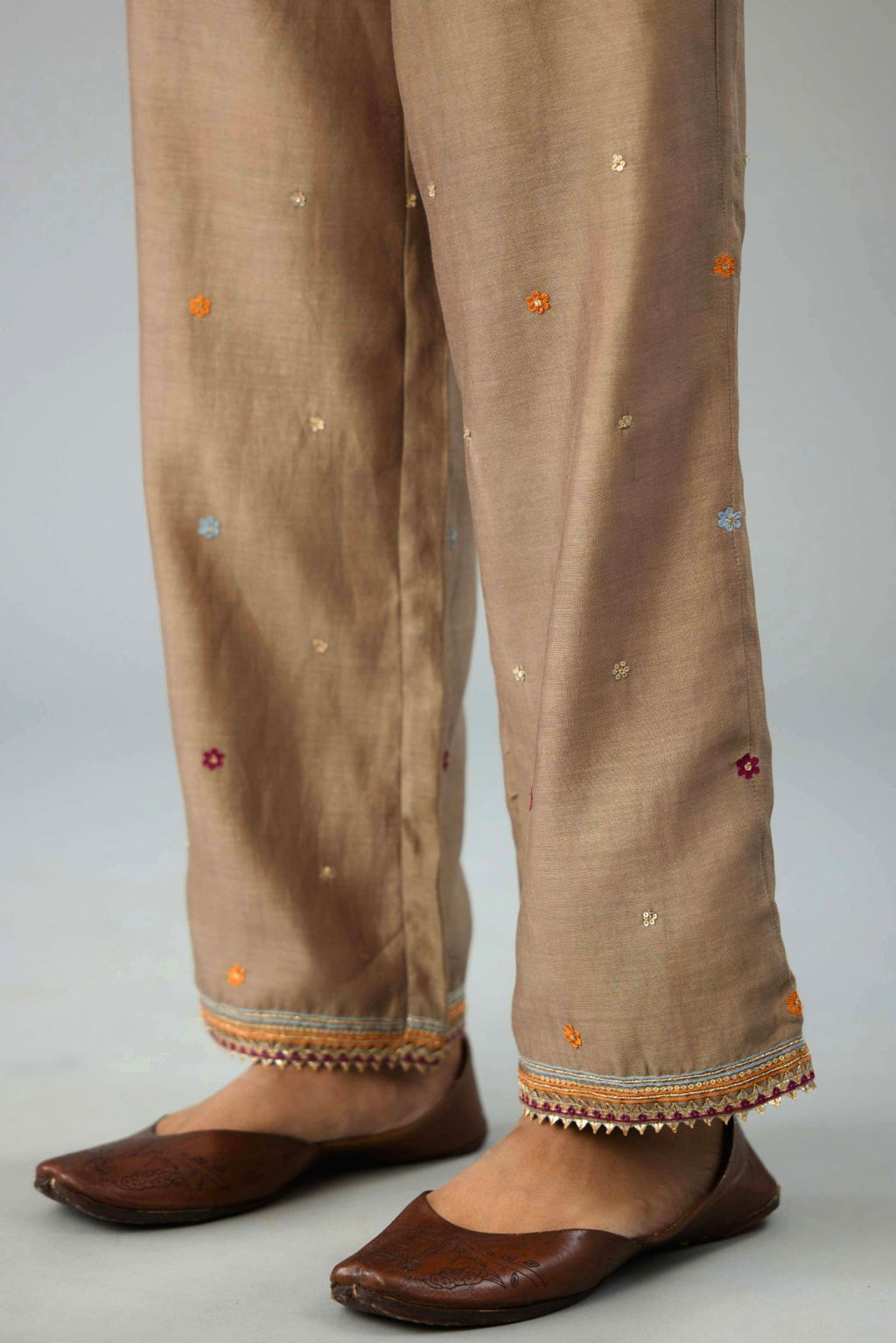 Taupe silk chanderi straight pants with dori and contrast silk thread embroidery,  detailed with gold sequins work.